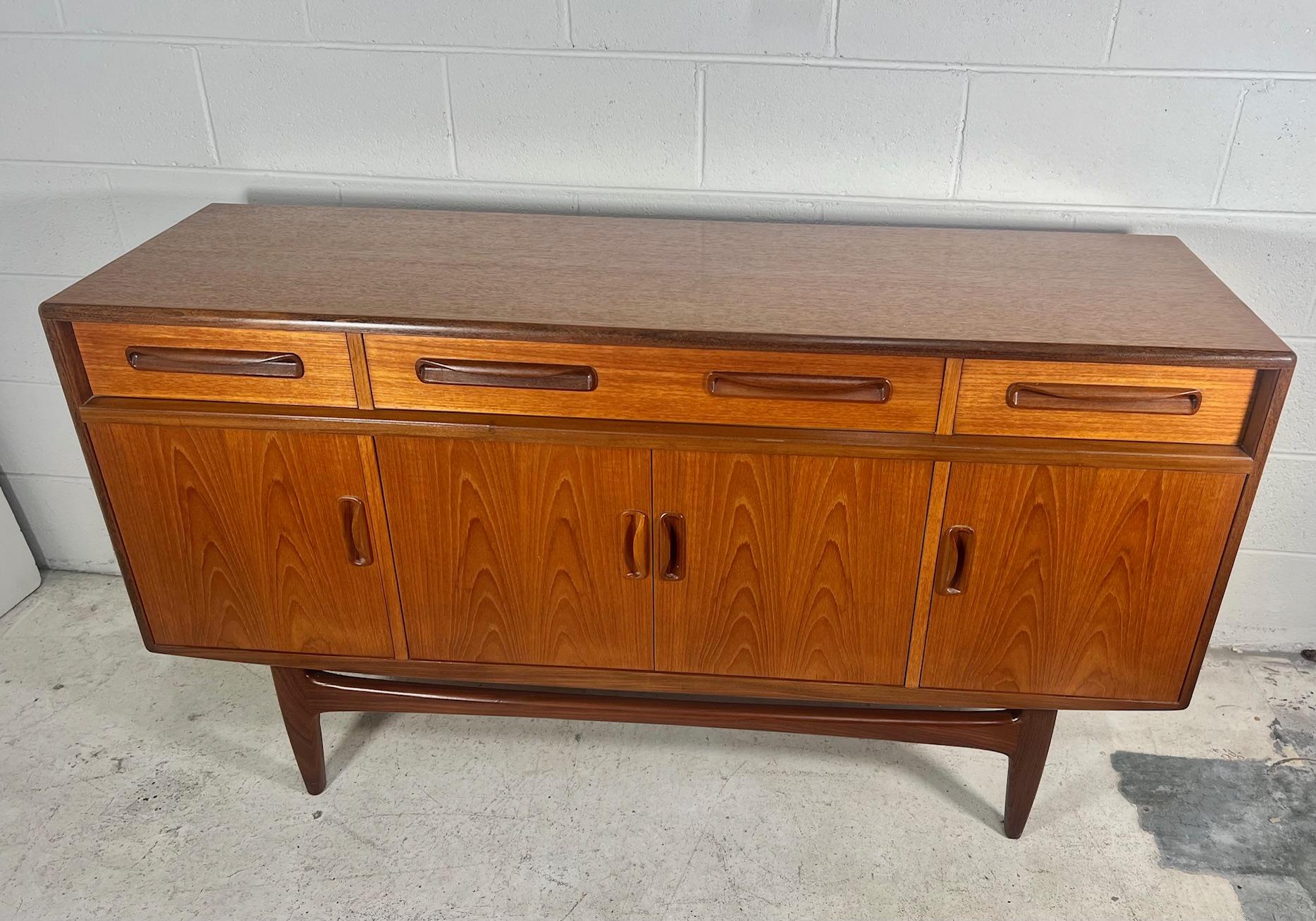 Outstanding small teak credenza. It was designed in the 1960s by Victor Bramwell Wilkins for G Plan's Fresco Range. It has original grey baize and wood dividers in the top drawer. Adjustable shelves inside the cabinets.
The back is unfinished.