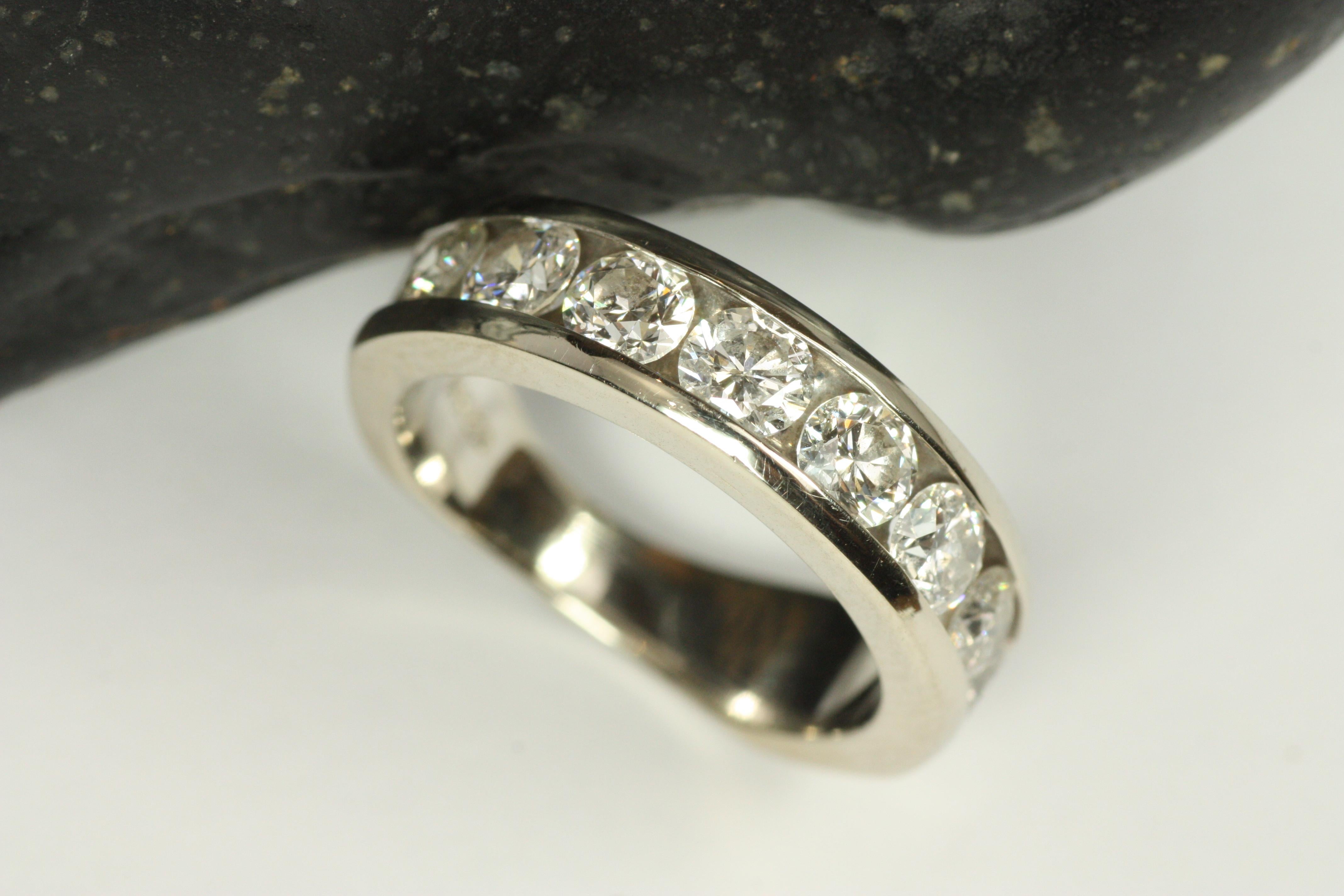 Alianza de oro blanco de 14 quilates con medio diamante engastado en canal. La anchura de 5,25 mm de la parte superior del anillo da cabida a 8 diamantes naturales de tamaño considerable, que suman 1,28 ct, y la caña cónica permite un ajuste cómodo.