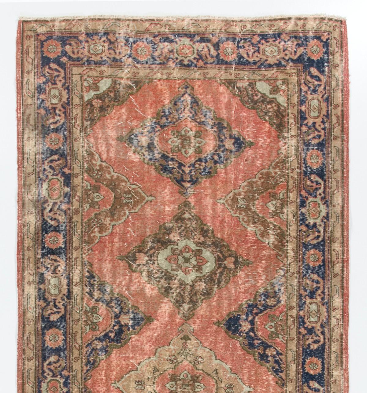 A vintage Turkish runner rug in red, navy blue, beige and green. It was hand-knotted in the 1960s with low wool on cotton foundation and features a multiple medallion design. It is in very good condition, professionally-washed, sturdy and suitable