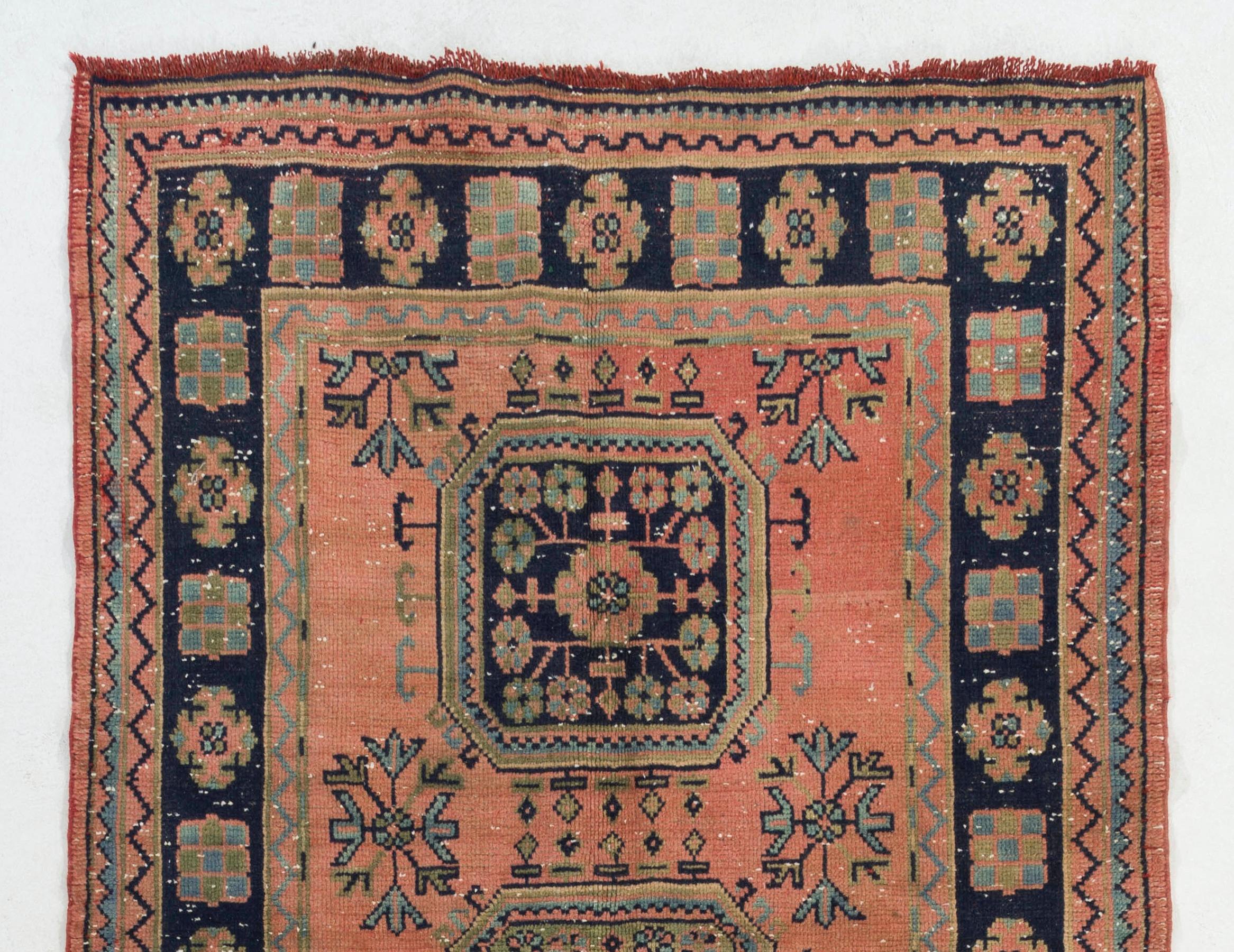 Ein türkischer Vintage-Läufer, handgeknüpft mit Wollflor auf Wollgrund. Es besteht aus miteinander verbundenen geradlinigen Medaillons, die mit floralen Kopfmotiven auf einem Feld in dunklem Korallenrosa verziert sind. Er ist in gutem Zustand,