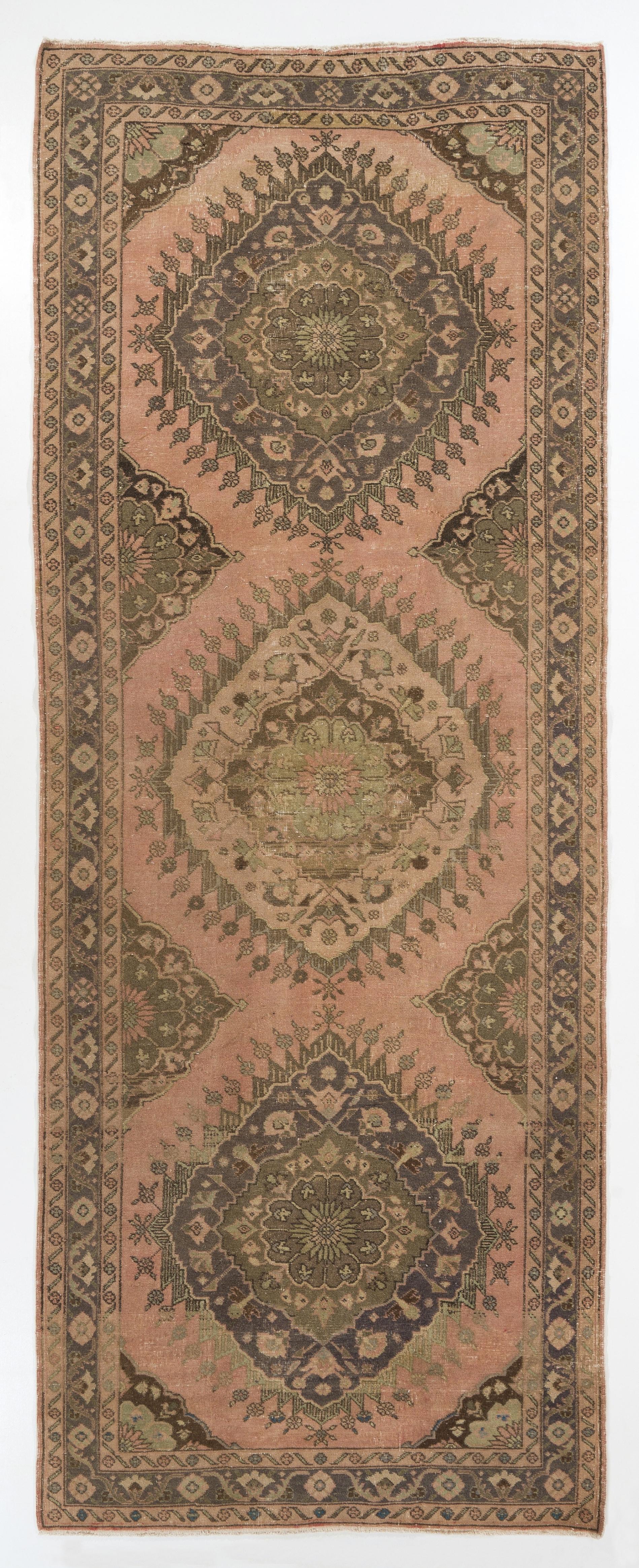A vintage Turkish runner rug. It was hand-knotted in the 1950s with even medium wool pile on wool foundation and features a multiple medallion design. It is in very good condition, professionally-washed, sturdy and suitable for areas with high foot