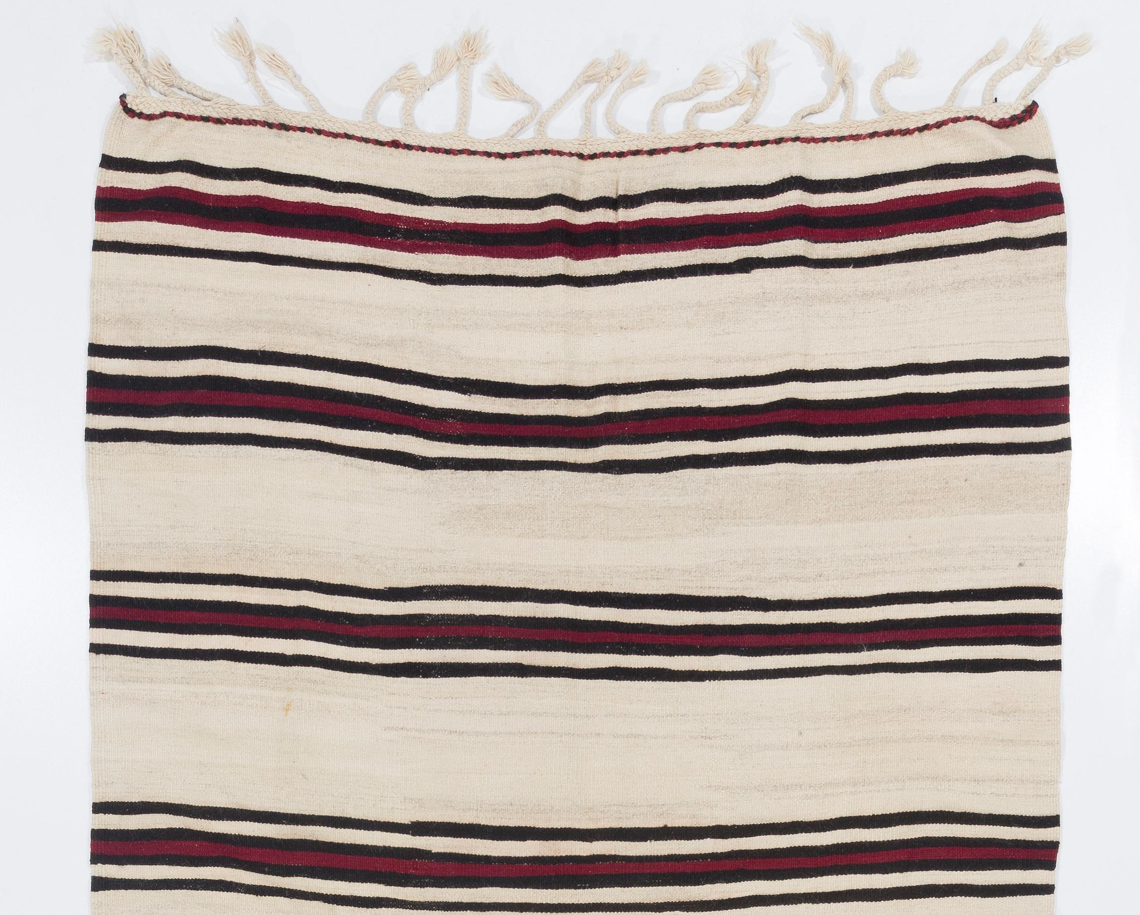 A vintage hand-woven Turkish kilim/flat-weave runner rug from the 1960s with a minimalist aesthetic. It was made entirely of natural, organic sheep's wool and features a simple striped design in brown and dark red against an un-dyed cream