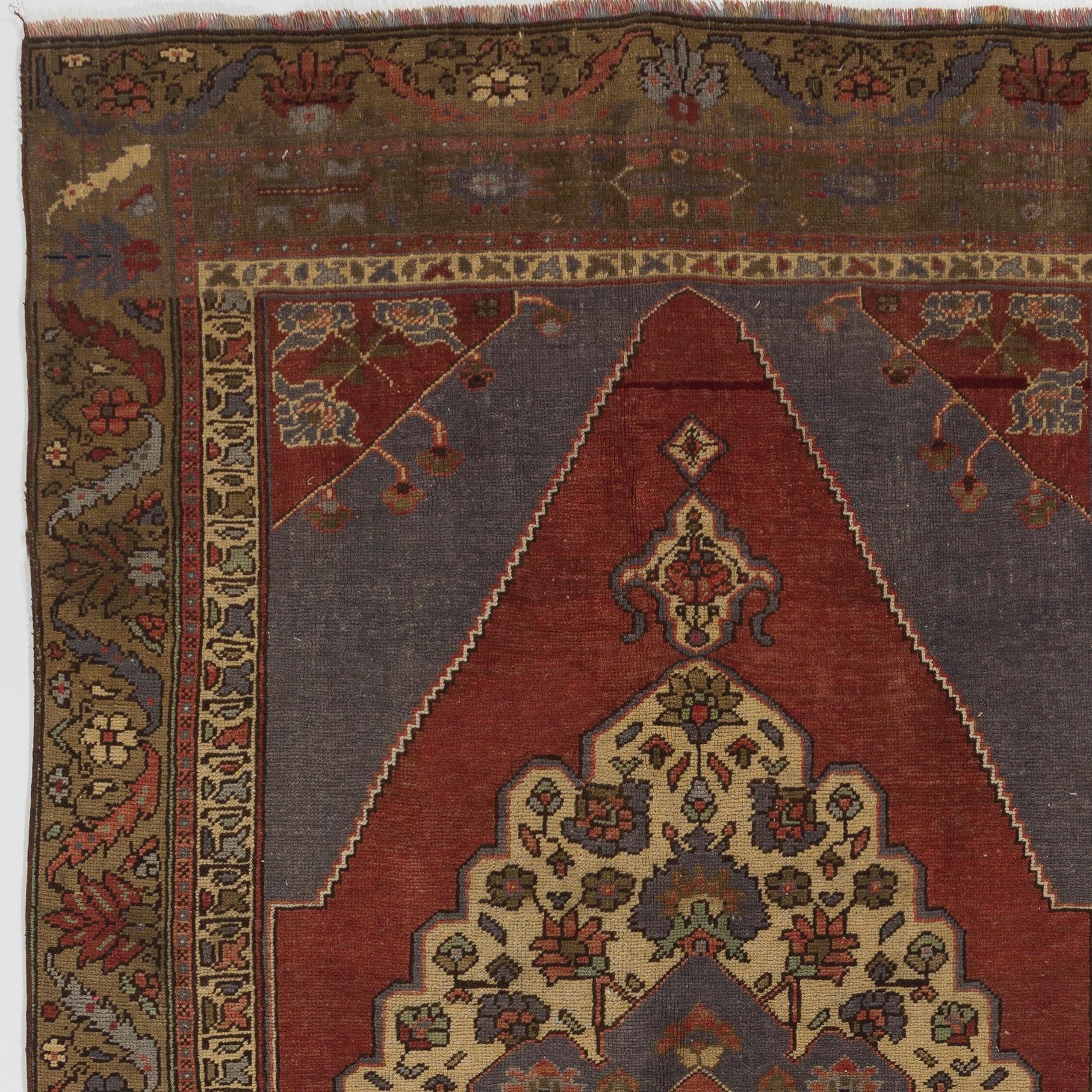 This room-size hand knotted vintage Turkish rug has at its center a prominent lozenge-shaped medallion in ivory that features scalloped edges and is decorated with free floating floral motifs around a smaller medallion in cerulean blue. The