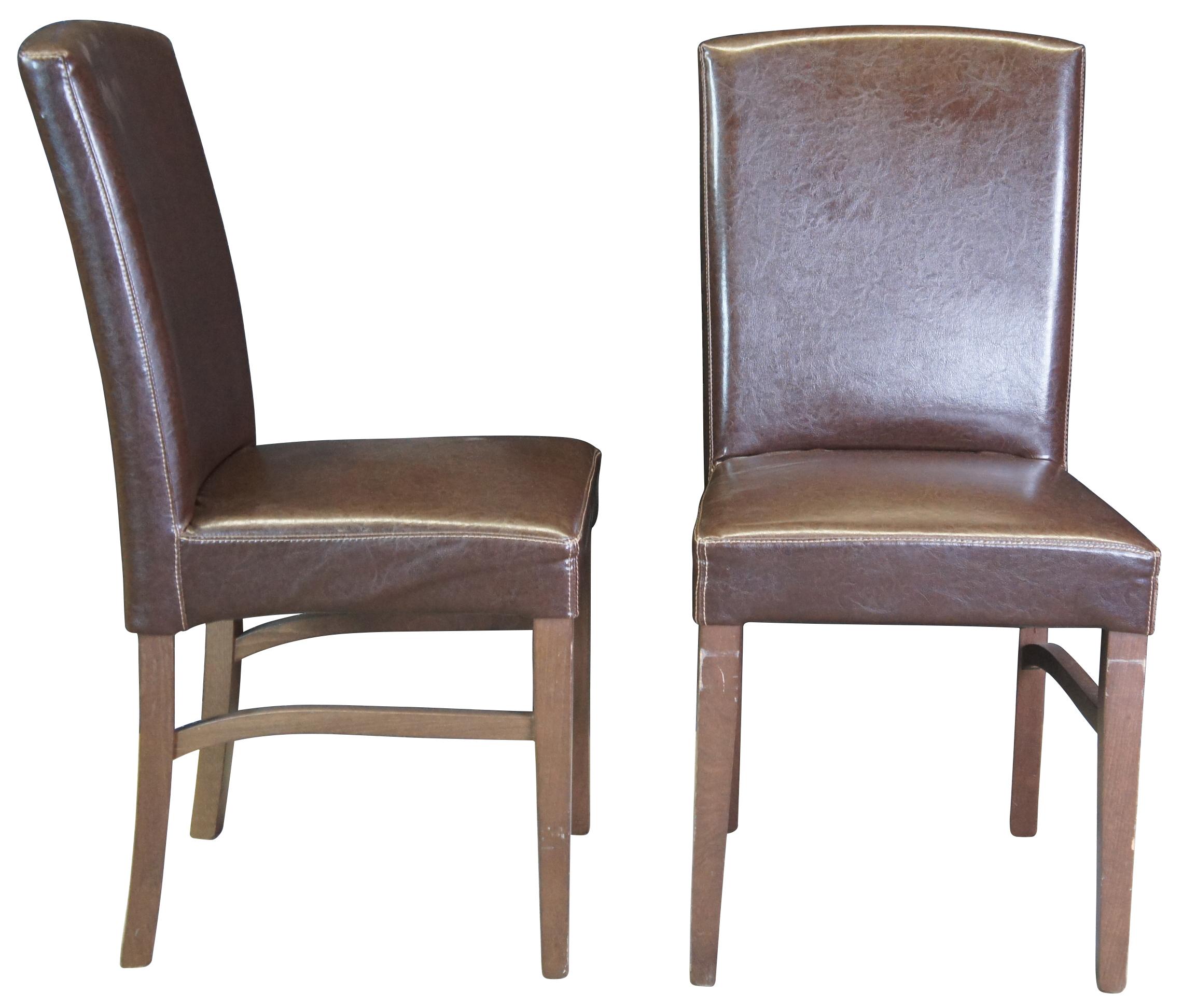 6 Arhaus Capri dining chairs. Each stool features a bowed crest rail with padded backrest and seat upholstered in a brown faux leather. They stand on brown stained tapered legs with shaped box-stretchers.