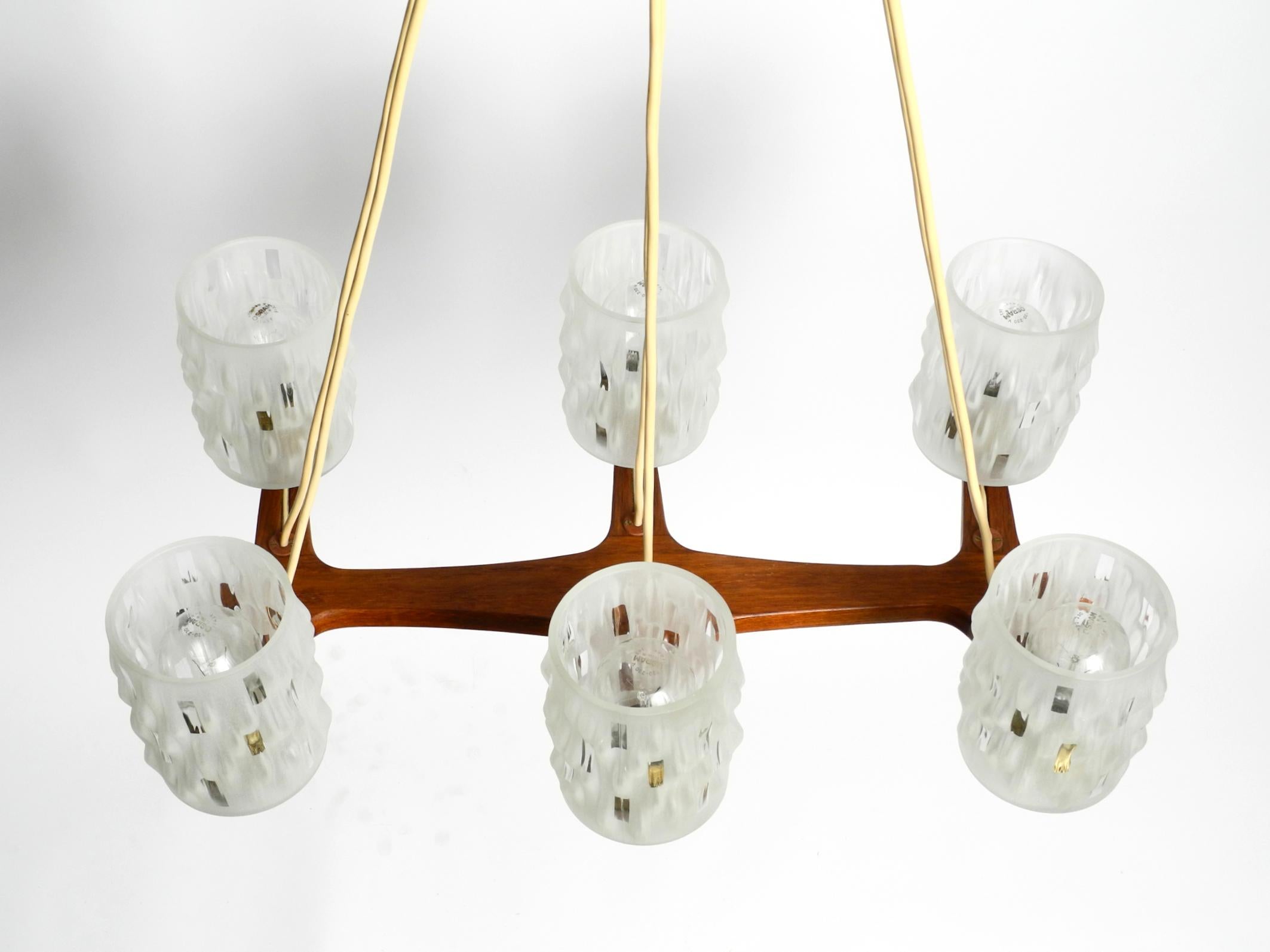 Bellissima lampada da soffitto in teak di grandi dimensioni con sei paralumi in vetro.
Produzione scandinava degli anni '60.
Grande, tipico design del Mid Century. Il telaio e il baldacchino sono realizzati in teak classico con una bellissima