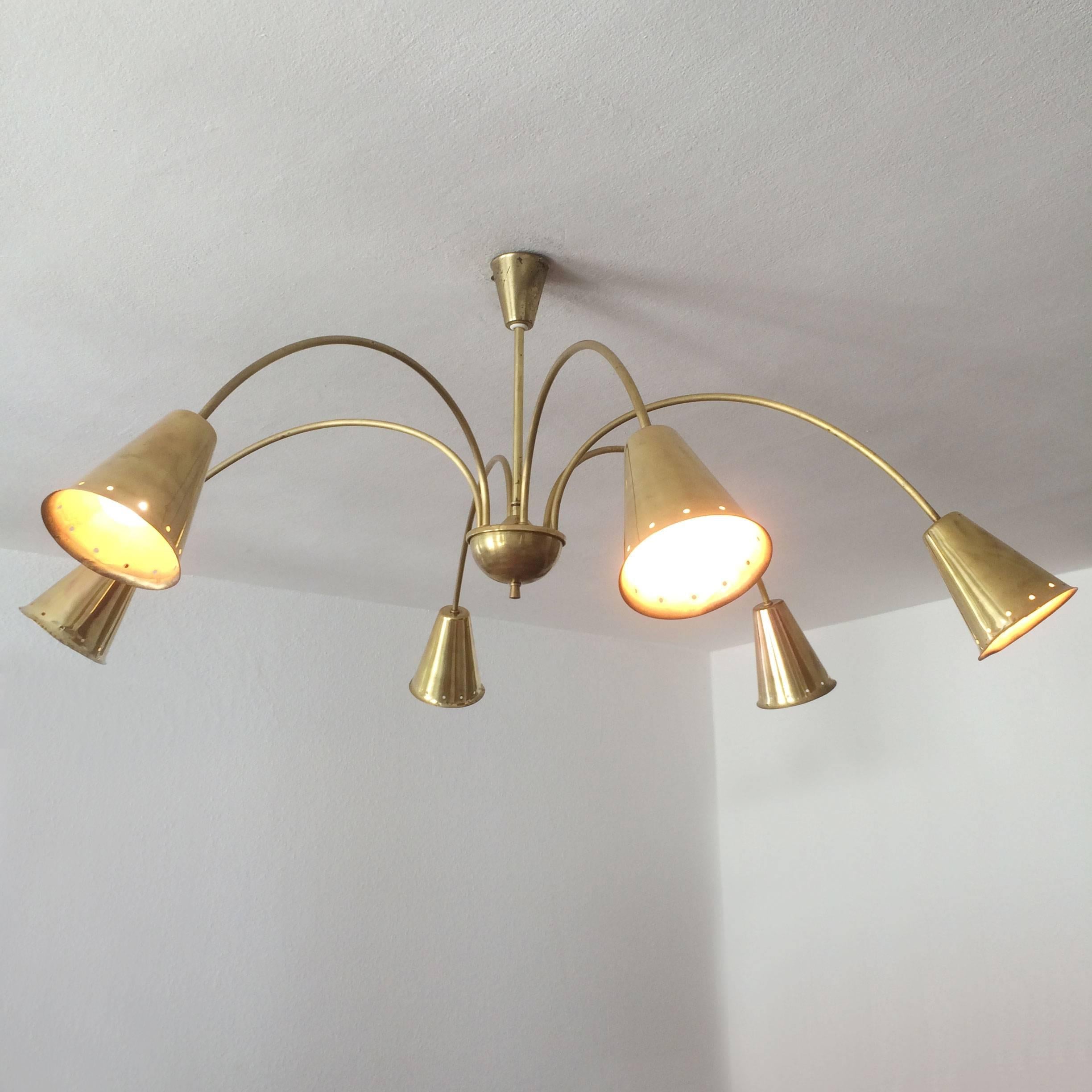Monumental Mid-Century Modern six-armed chandelier or pendant light with perforated large lamp shades in brass. Designed and manufactured probably in Germany in 1950s.
The lamp is executed with six E27 screw fit bulb holders, wired and in working