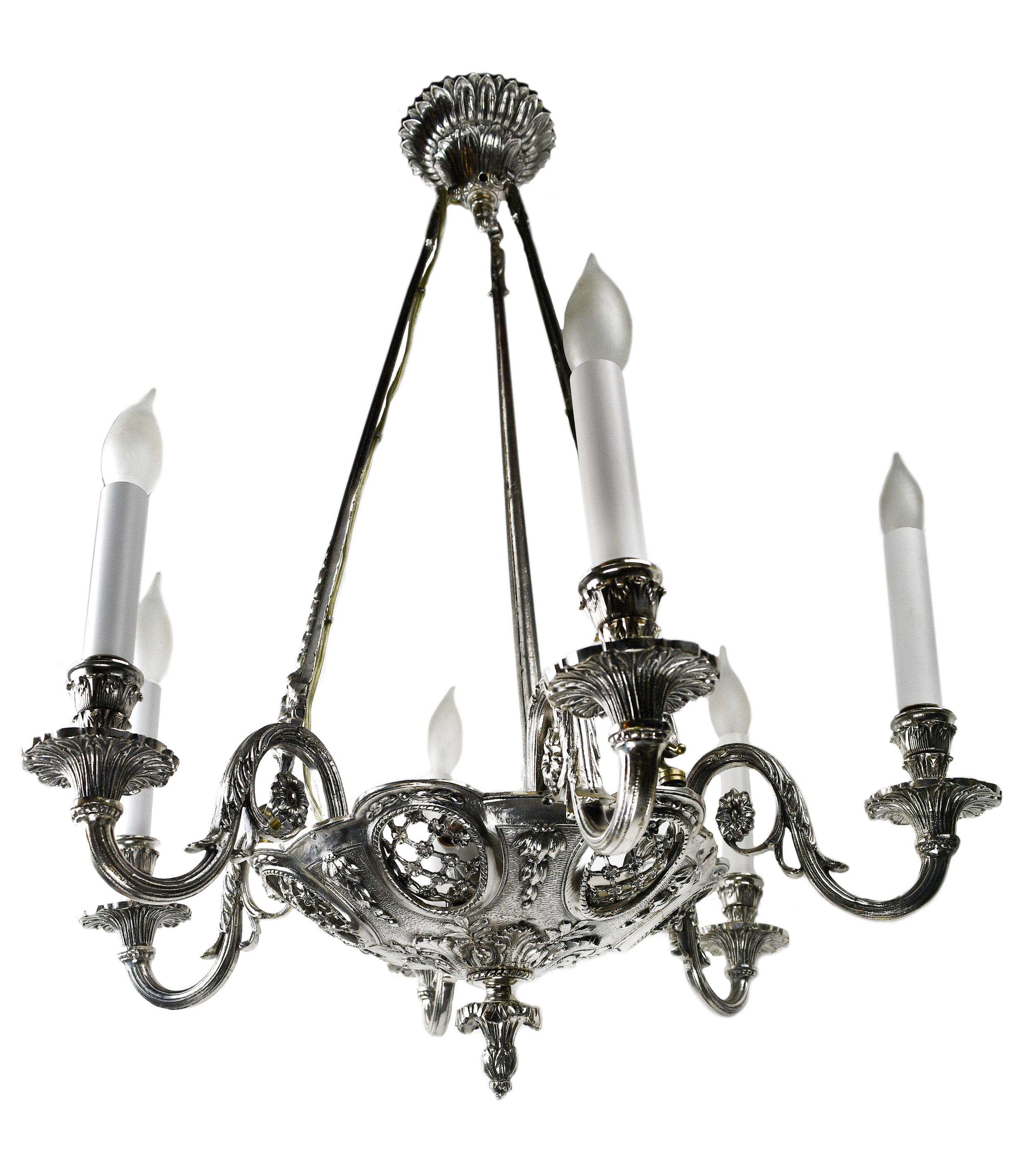 This stunning chandelier has lovely silver plating and features unique face designs and an intricately detailed floral pattern. The fine craftsmanship found through within the silver plating of this chandelier is truly eye-catching! 3 candelabra