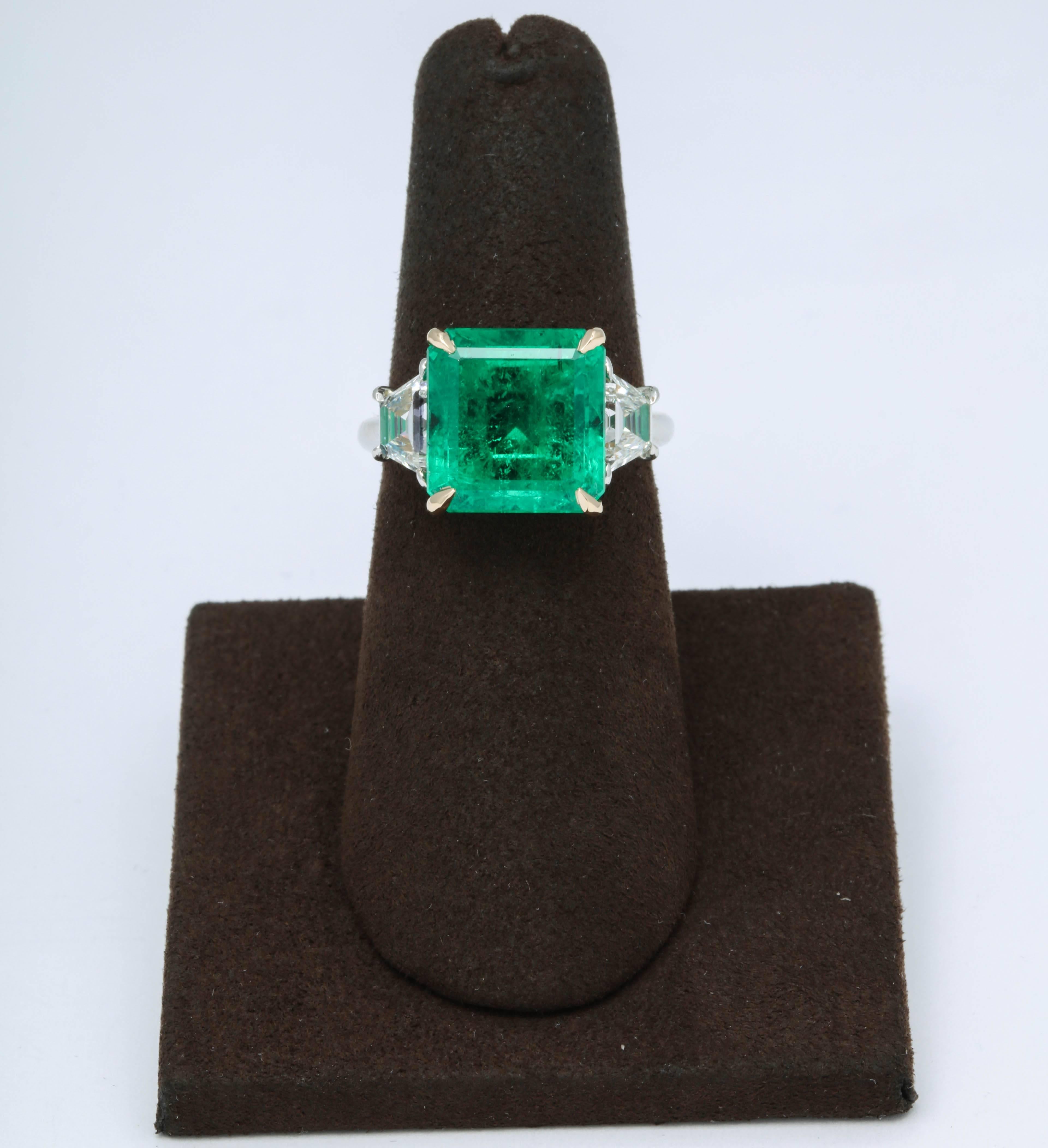 
A very fine emerald ring -- superb color and luster!

6.15 carat GIA certified Colombian Emerald ring F1.

Set in a custom platinum and 18k yellow gold mounting with 1.05 carats of step cut trapezoid diamonds. 

Currently a size 6, this ring can
