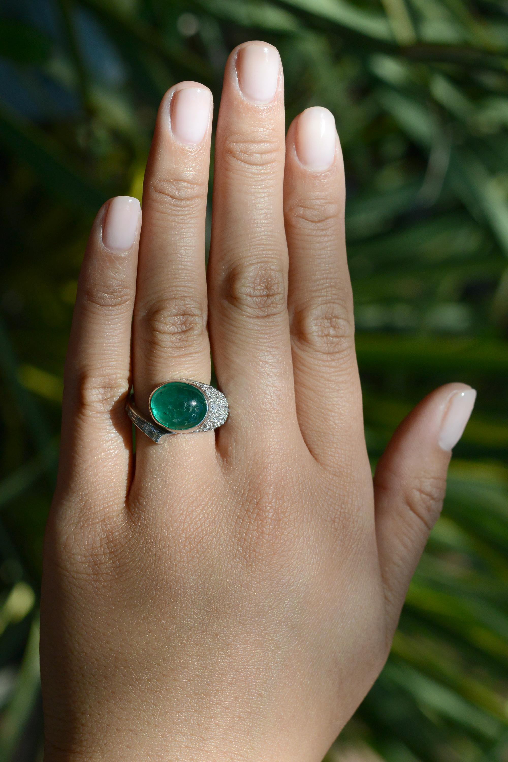 Be transported back to the luxurious glamour of the roaring twenties with this authentic Art Deco ring. Crafted with a unique asymmetrical platinum setting, this ring features a glowing 6.07 carat cabochon Colombian emerald, accented with antique