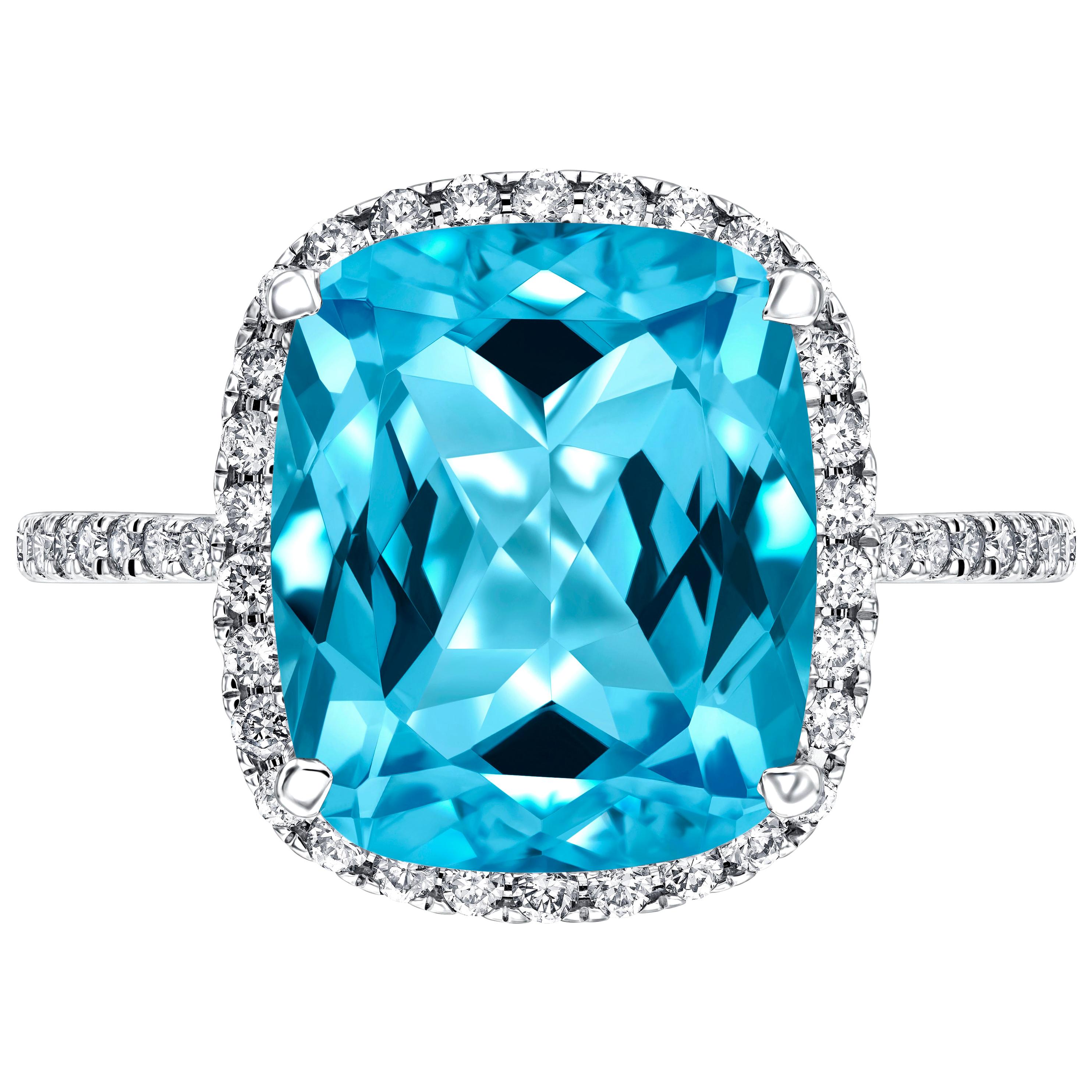 Une impressionnante bague de fiançailles de 6 carats (environ) en topaze bleue taillée en coussin, entourée d'un halo pavé et des deux côtés de la tige. Le poids total des diamants est de 0,38 carat de diamants ronds de taille brillant. 

Cette