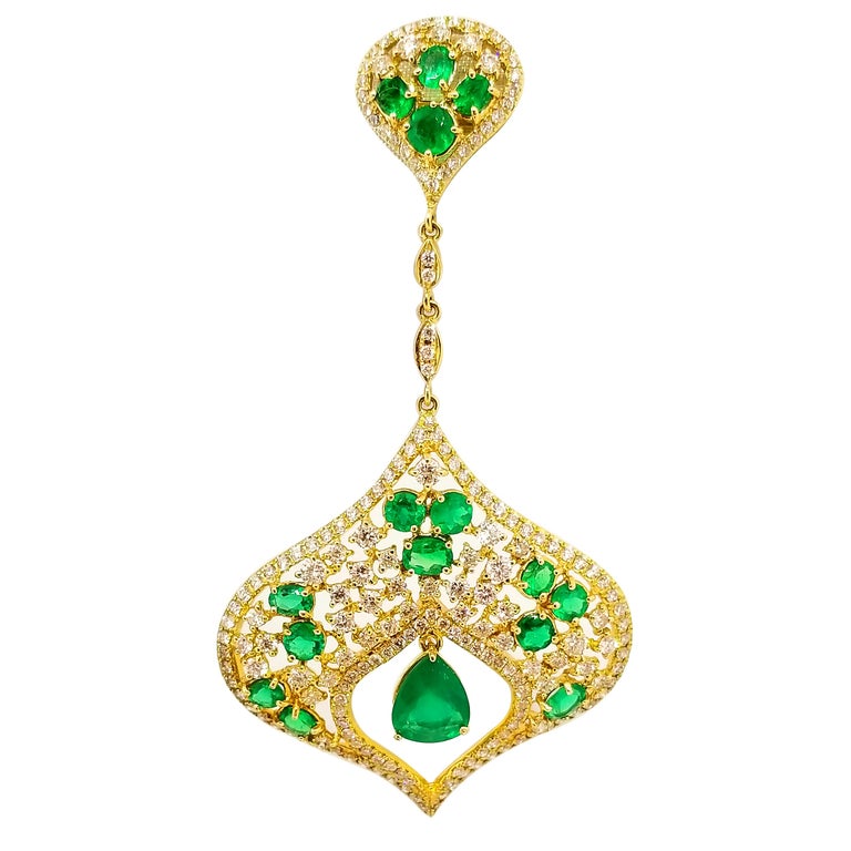 Long and Elegant Statement Earrings of Emerald and Diamonds in 18K Yellow Gold. The Intricately Crafted Earrings feature faceted, Oval, Round and Pear Shape Emeralds of Rich Grass Green hue and Gem Quality. The stones are of very fine quality and