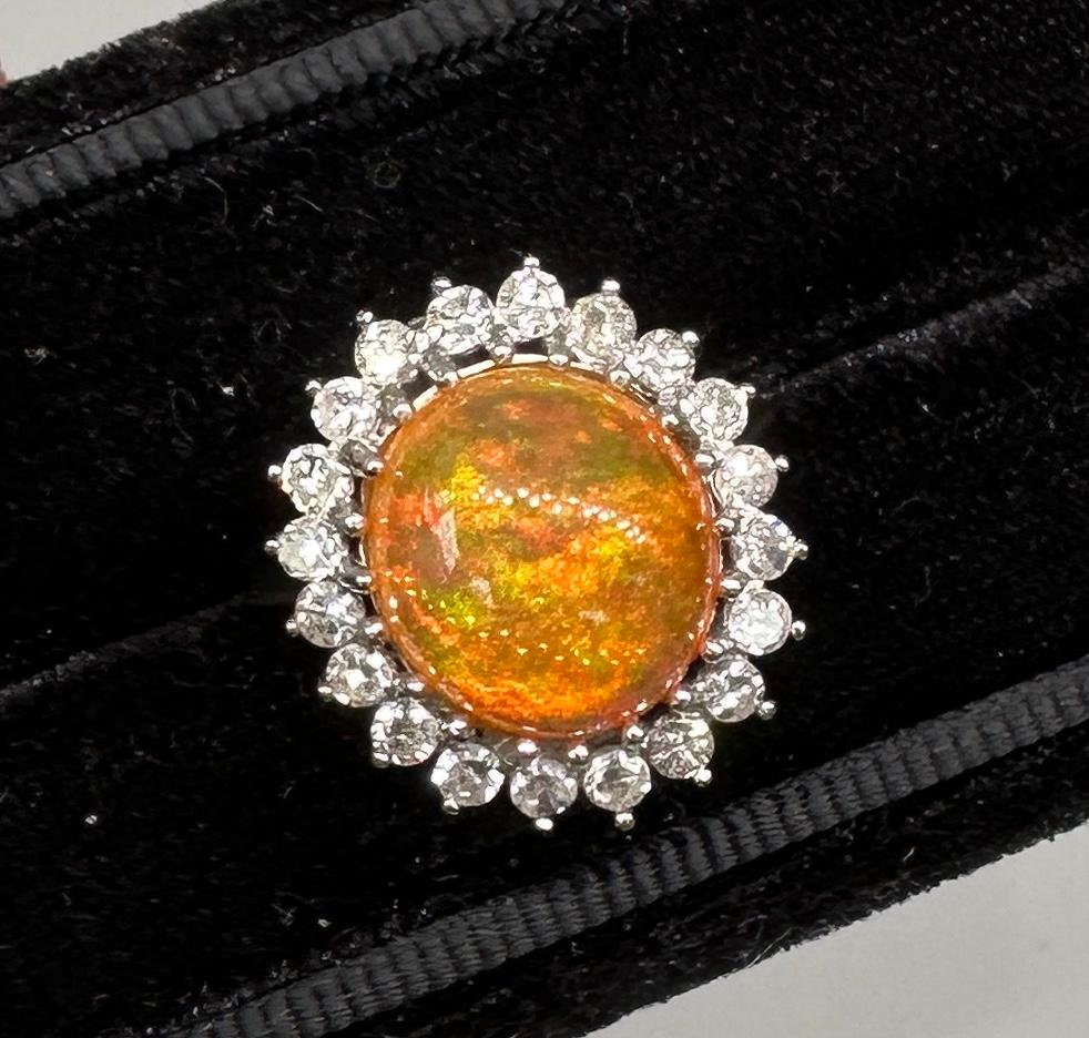 This is a spectacular antique Mexican Fire Opal 20 Diamond Ring.  The ring is 14 Karat White Gold.  The sparkling oval Mexican Fire Opal is approximately 6 Carats and is one of the most gorgeous fire opals we have seen.  The opal cabochon has