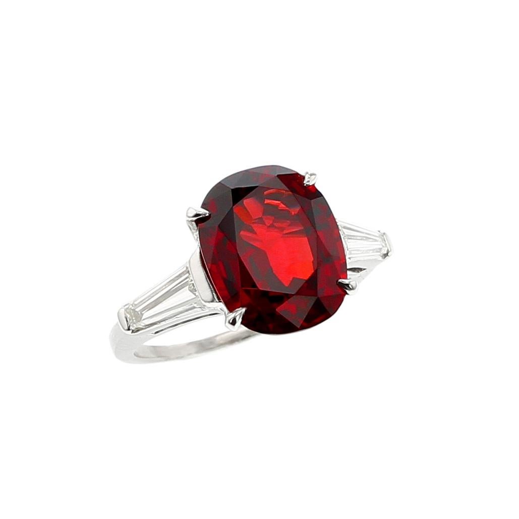 A beautiful three-stone platinum ring centered with a vibrant natural, no-heat red spinel from the coveted region of Burma (Myanmar), weighing over six carats, with two tapered baguette diamonds, weighing approximately 0.50 carats., with an