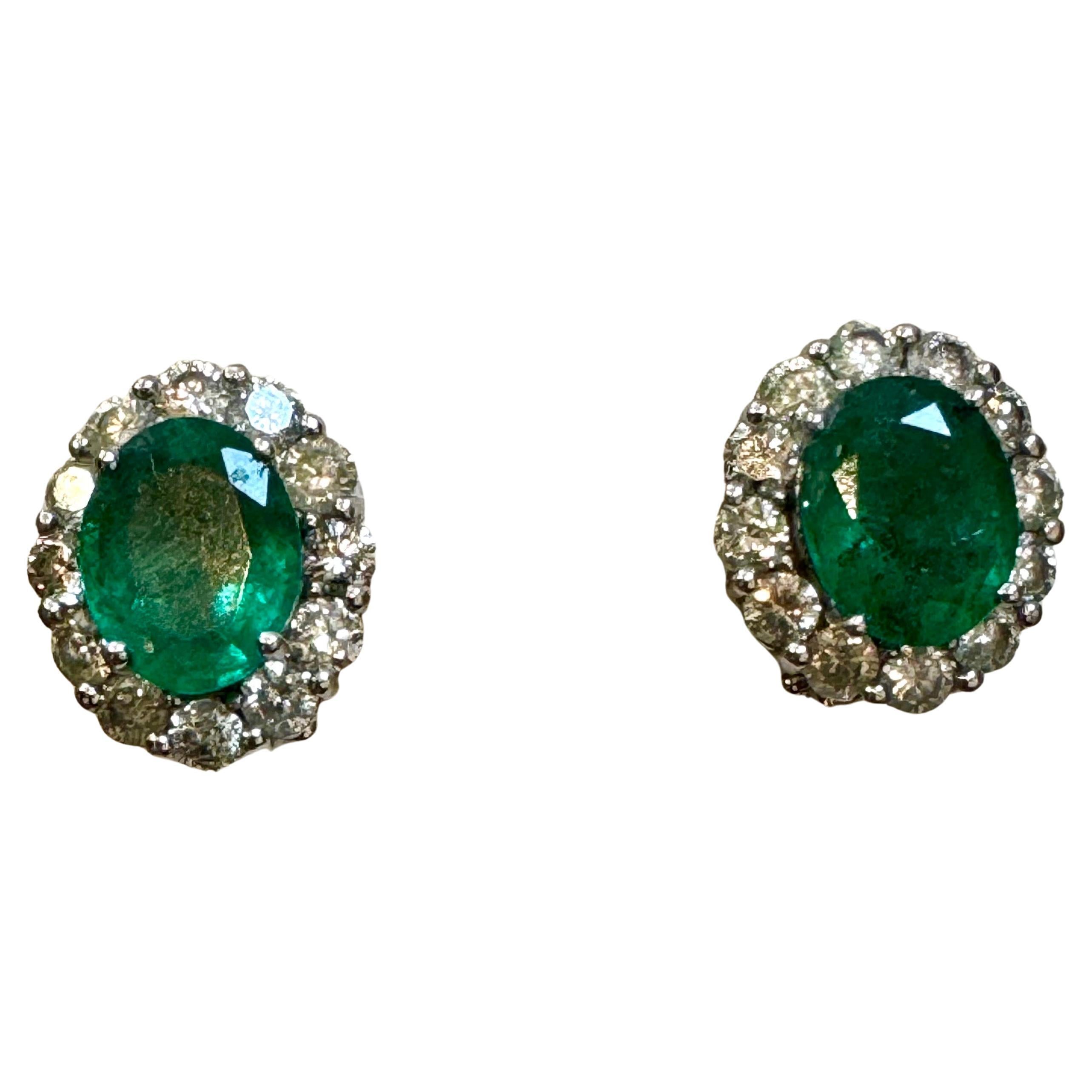These stunning post back earrings with French clip feature a natural oval-shaped emerald weighing total approximately 6 carats, accompanied by brilliant round cut diamonds. Each emerald is 3 ct . The emeralds are of very fine quality with a