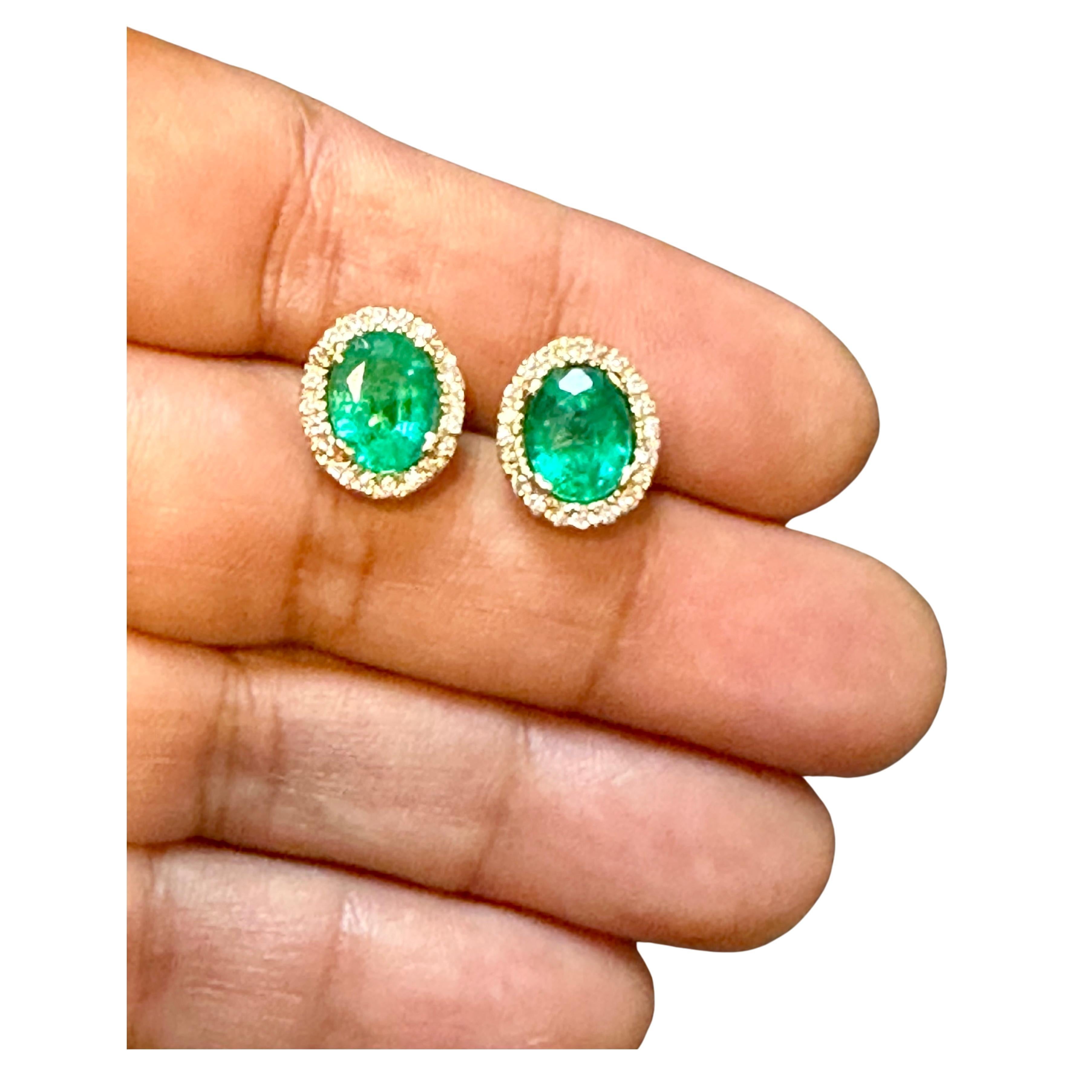 These stunning post back earrings feature a natural oval-shaped emerald weighing total approximately 6 carats, accompanied by brilliant round cut diamonds. Each emerald is 3 ct . The emeralds are of very fine quality with a beautiful color,