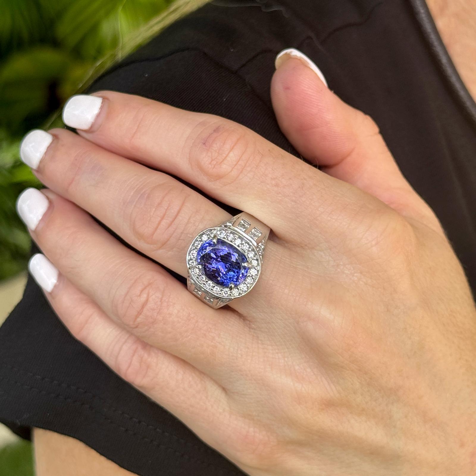 This exquisite 18 karat white gold ring highlights a stunning oval tanzanite of approximately 6.26 carats, celebrated for its rich blue-violet hue and exceptional brilliance. Surrounding the centerpiece are 28 round brilliant-cut diamonds and 16