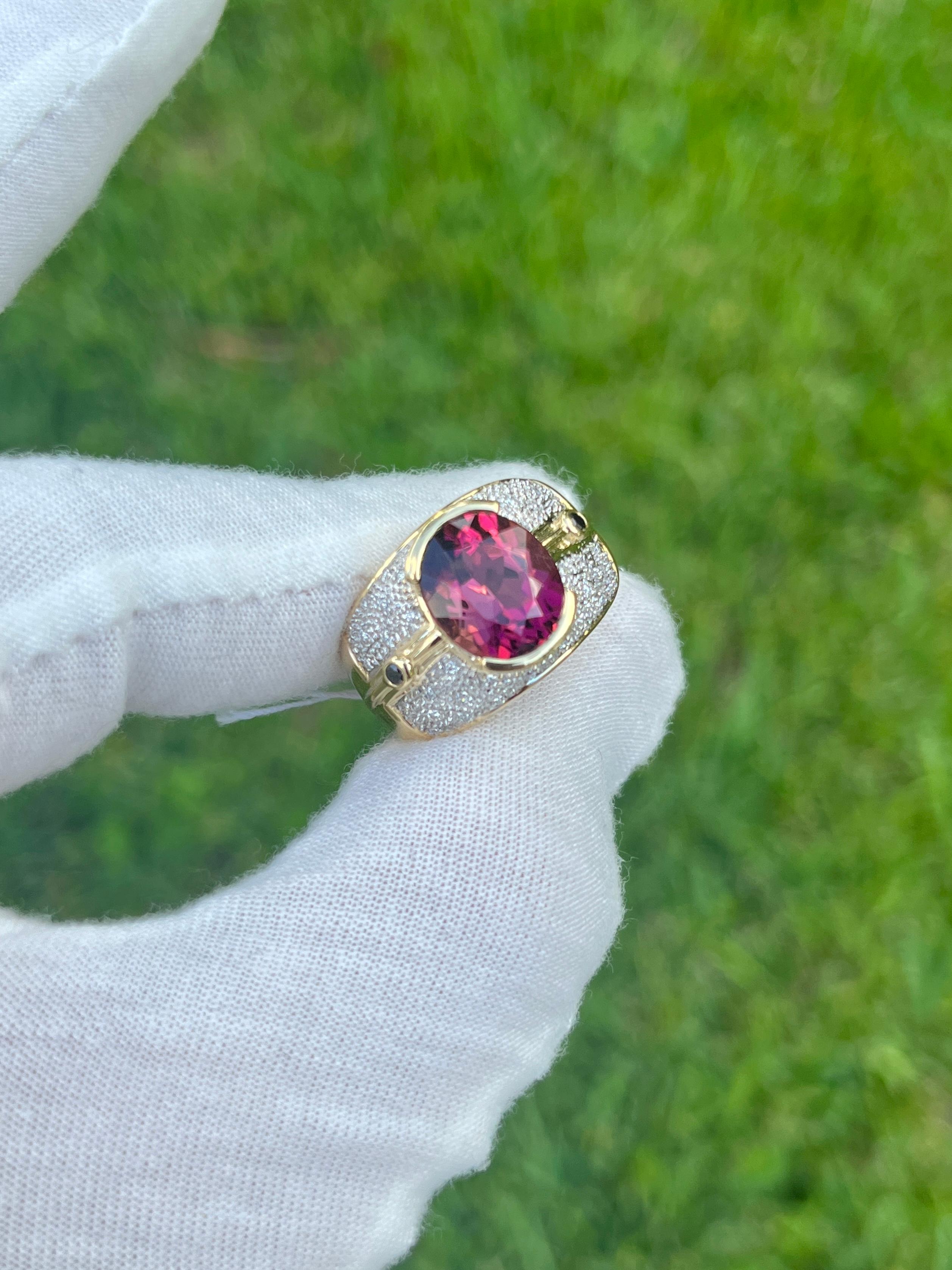 Vintage 6 Carat Pinkish Red Oval Cut Tourmaline Ring. Set in 18K Yellow Gold, this semi-precious gemstone ring weighs 11.5 grams and styles the a retro era look.

The exquisite oval-cut tourmaline, with a charismatic blend of pink and red hues,