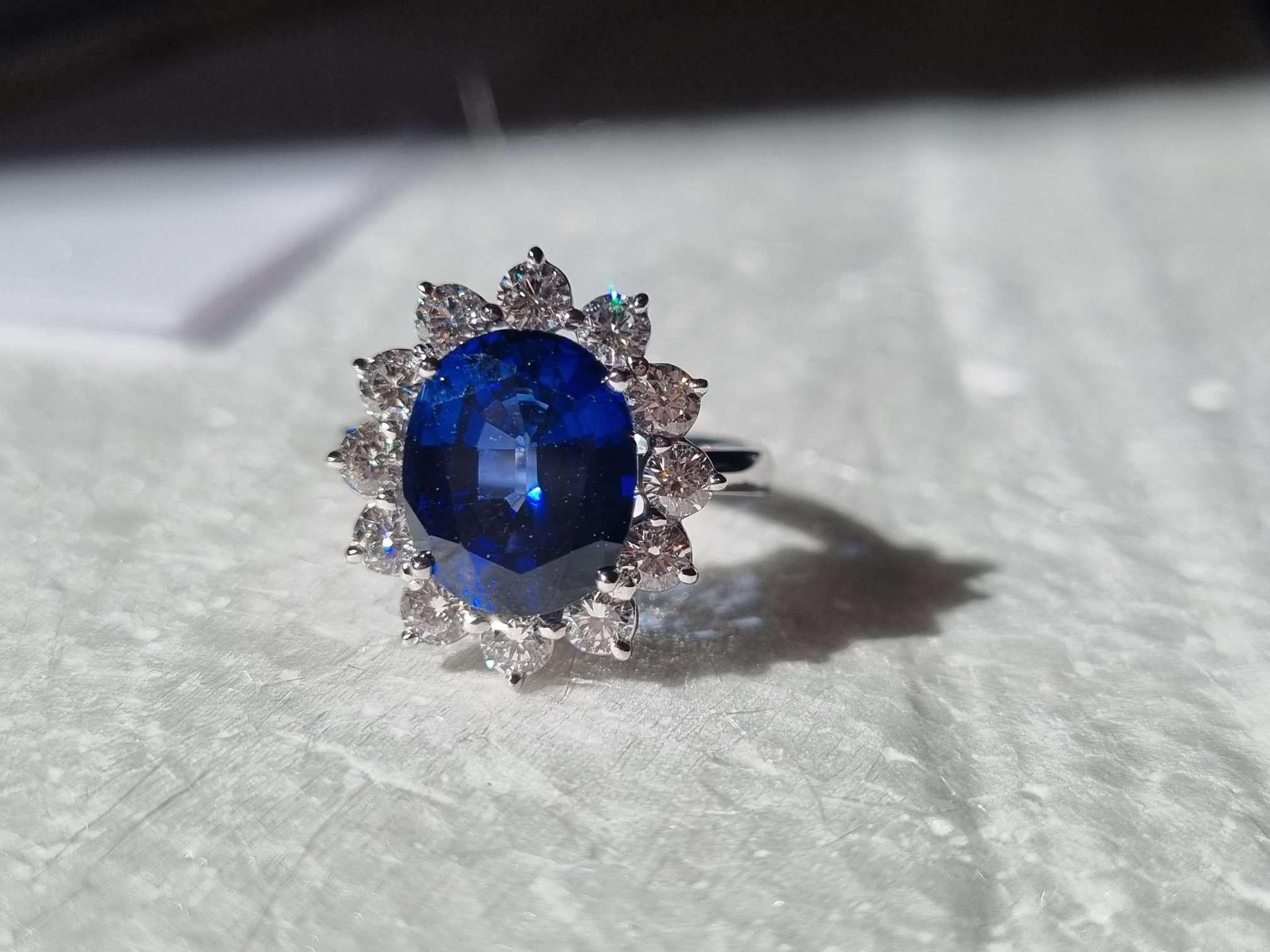 This immense oval-cut halo ring is truly glorious! It features a lush 5.98 carat Royal Blue Sapphire, lab grown, surrounded by a halo of gorgeous natural brilliant cut VVS diamonds totaling 1.00 ct, in a solid 18ct White Gold setting. This is such a