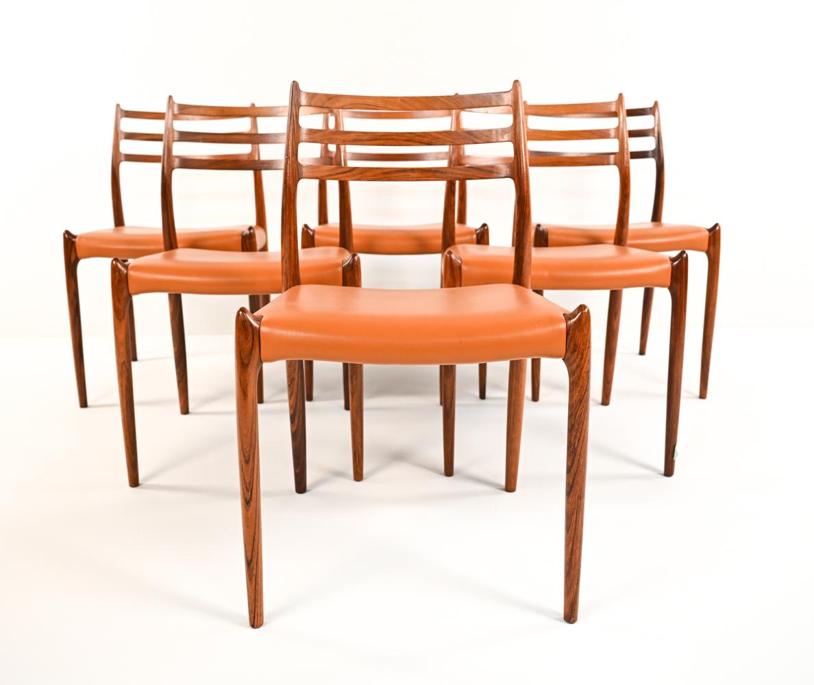 An attractive set of (6) Danish mid-century model 78 dining/side chairs by N. O Møller for JL Møllers Møbelfabrik, c. 1960s. Featuring handsome rosewood frames with orange leather seat upholstery.