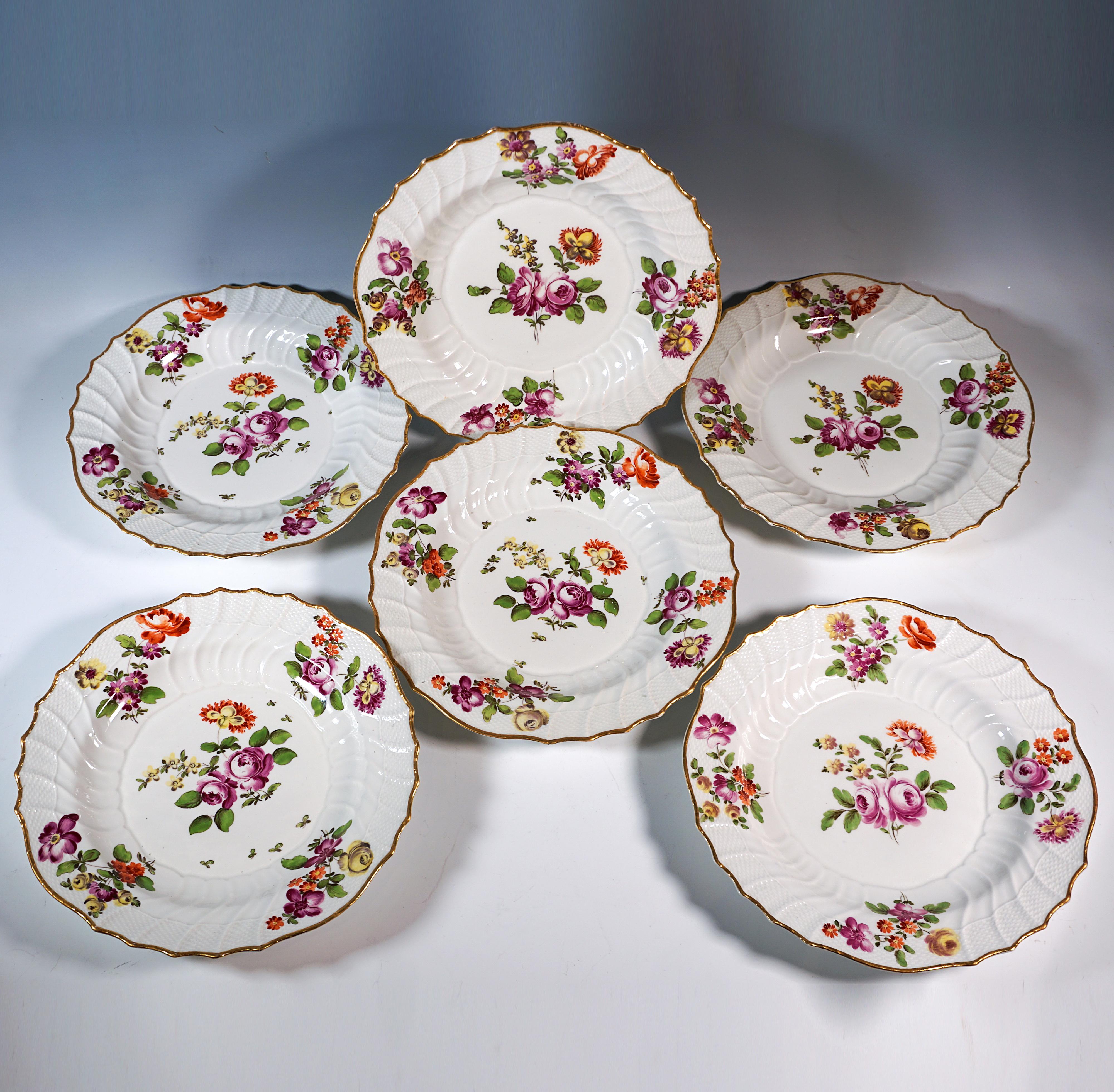 Six assiettes en porcelaine ancienne avec peinture florale polychrome : petits bouquets de fleurs de prairie en rouge de fer, violet, jaune et vert au centre et sur le bord, ainsi que des feuilles éparses et un liseré d'or. Surface gaufrée 
basé sur