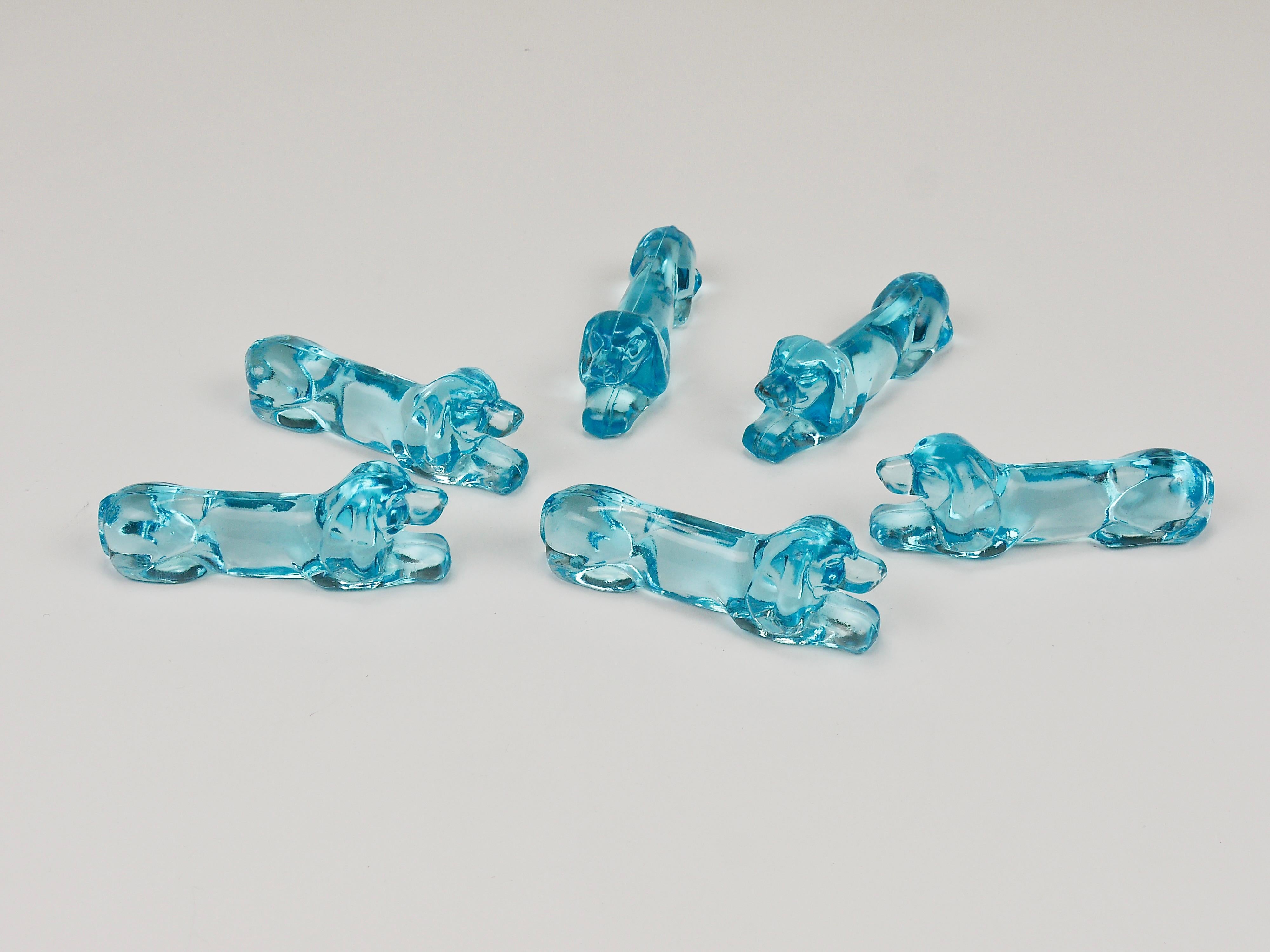 A set of 6 utterly charming 1930s Art Deco glass dog rests for knives, featuring a delightful depiction of a dog—possibly a Basset Hound or a Dachshund / Sausage Dog / Wiener Dog. Crafted from pale blue pressed glass in France during the 1930s,