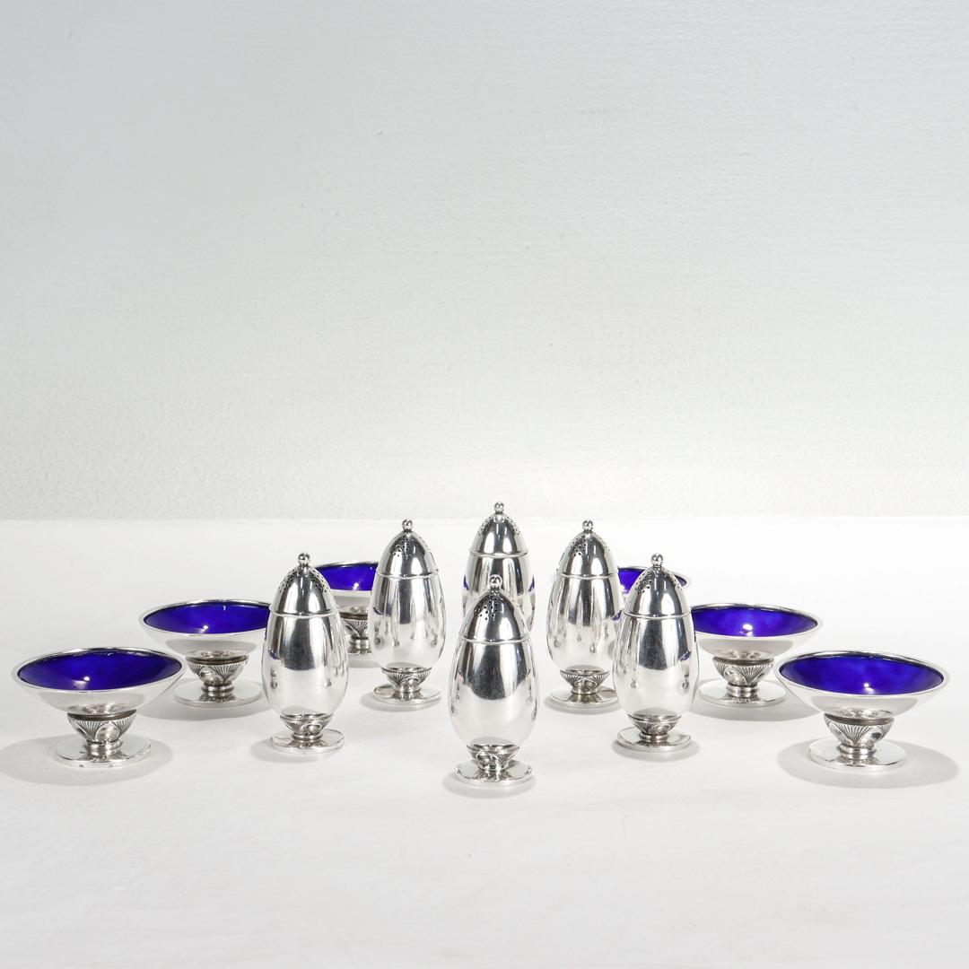 A fine group of 6 salt and pepper sets.

In sterling silver with blue enamel to the salt cellars.

By Georg Jensen.

In the Cactus pattern.

Designed by Gundorph Albertus in the early 1930's.

Comprising 6 pepper shakers, 6 salt cellars with blue