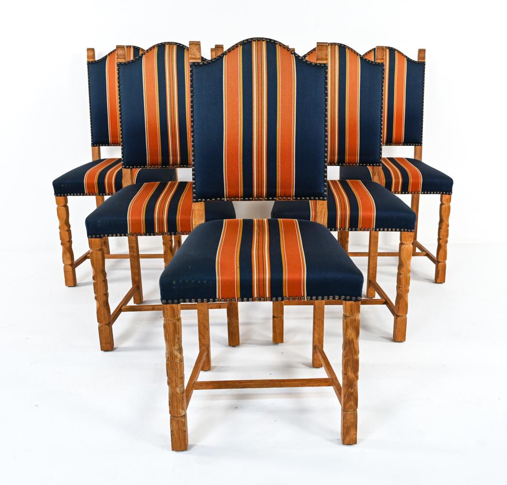 A set of six Danish mid-century dining side chairs in the manner of designer Henning Kjaernulf, well-renowned for his iconic farmhouse-inspired carved oak furniture designs, c. 1960's. These charming provincial chairs feature high shaped backs,