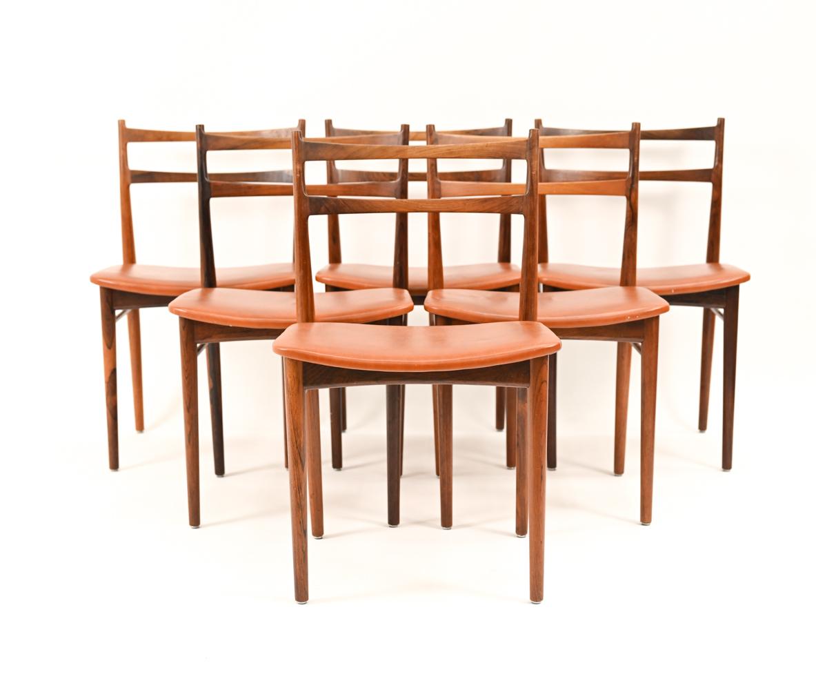 Un bel ensemble de chaises de salle à manger danoises du milieu du siècle, conçues par Henry Rosengren Hansen pour Brande Mobelindustri. Les fauteuils sont dotés d'un élégant dossier en bois de rose incurvé et d'une assise en cuir cognac. Marqué