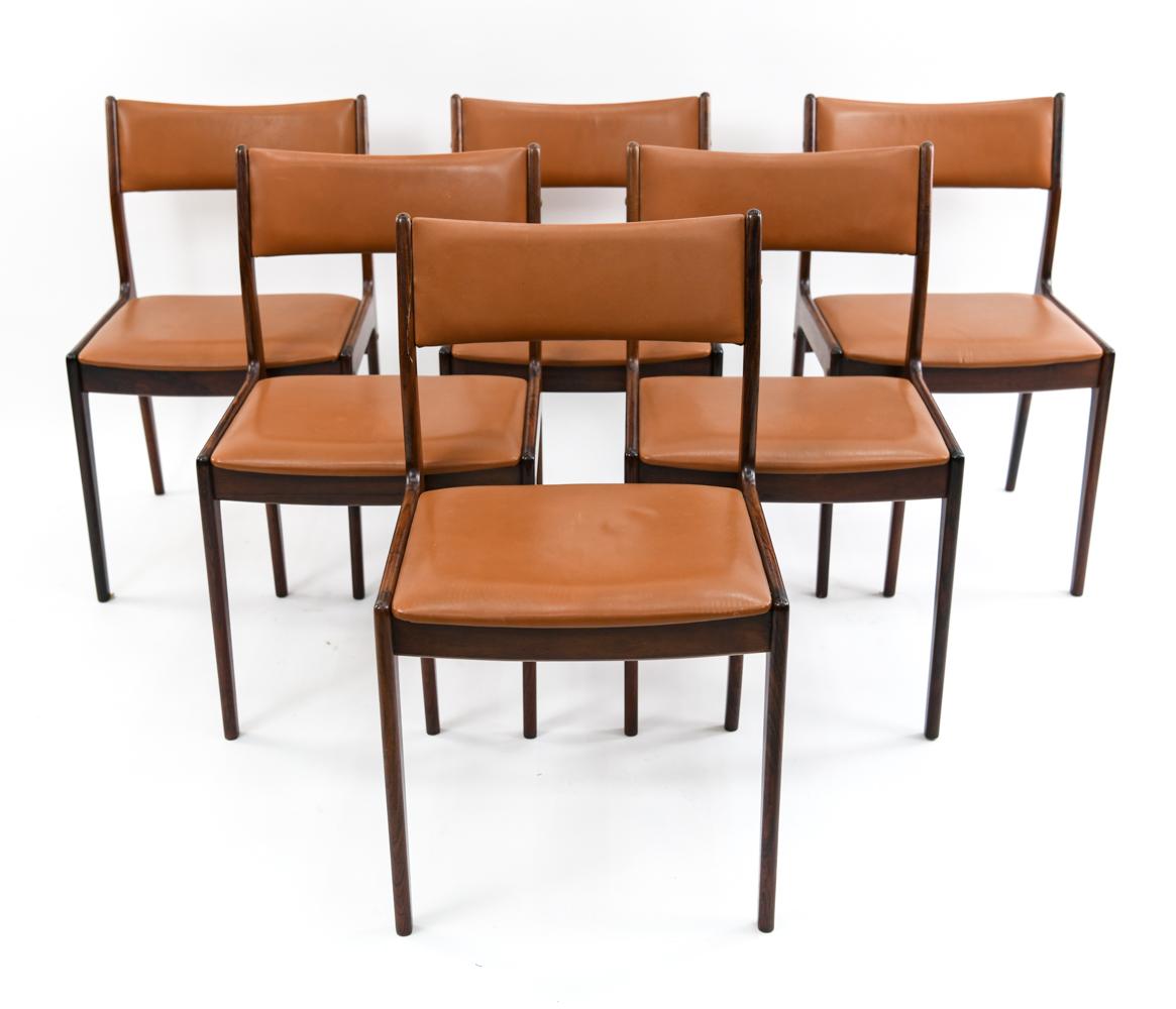 A set of six 1960s Danish modern rosewood dining chairs by designer Johannes Andersen, made in Denmark by Uldum Møbelfabrik: model UM85. These chairs feature attractively curved backrests with rosewood frames and seat/backrest upholstery in burnt