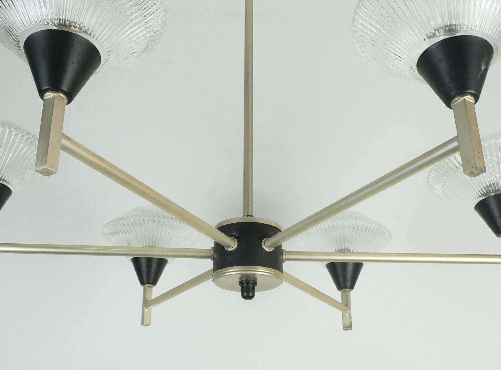 Bellissimo lampadario della metà del secolo scorso, risalente ai primi anni '60. Telaio in alluminio anodizzato e metallo verniciato nero, 6 paralumi in vetro trasparente strutturato. Può contenere lampadine E14.
 
Dimensioni in cm:
Lunghezza 69 cm,