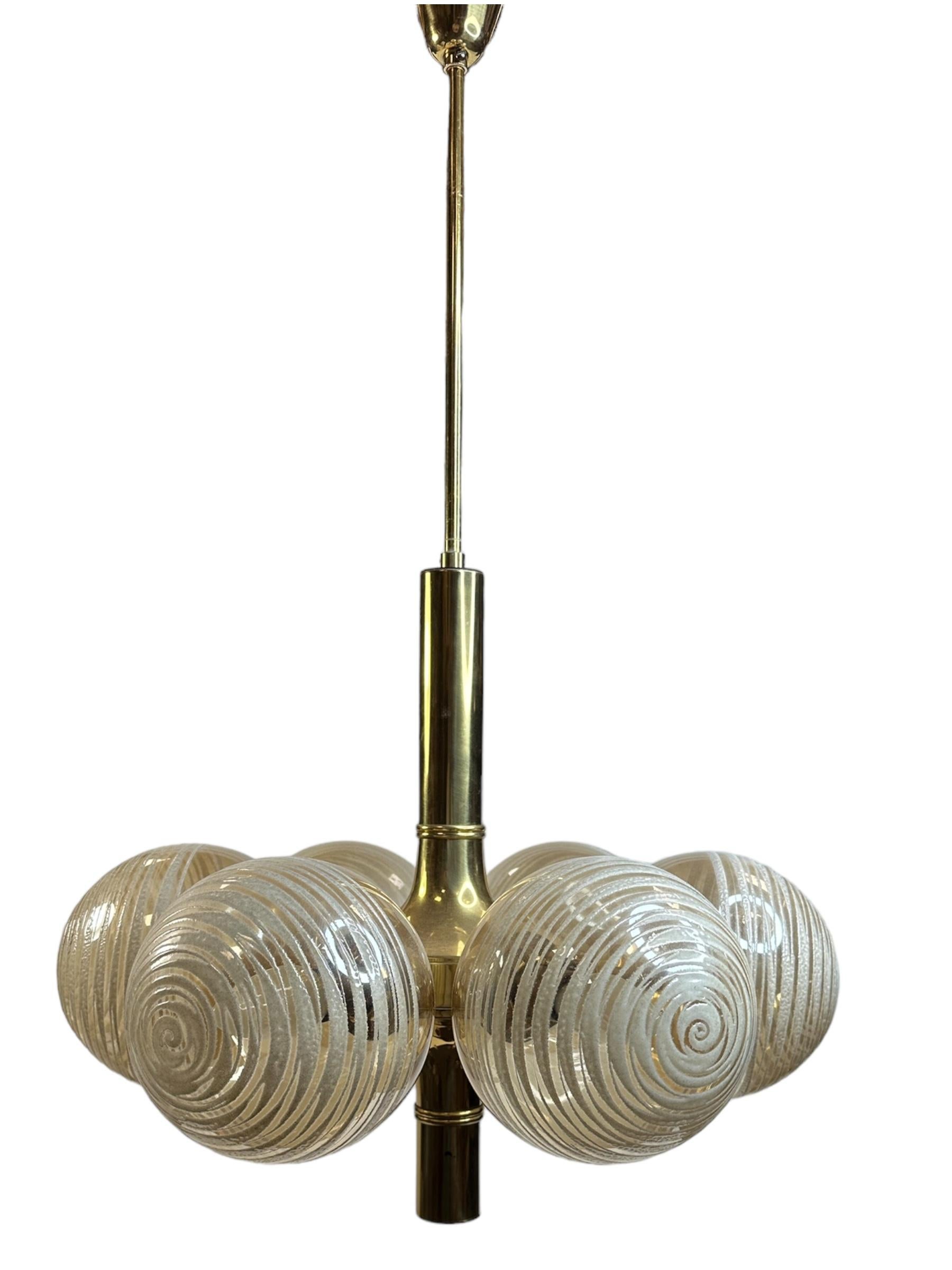 Très décoratif et beau lustre en laiton, équipé de six douilles E14 avec des abat-jours en verre tourbillonnant. Lustre vintage en laiton doré et verre de couleur ambre d'une beauté exceptionnelle est parfait pour être installé au plafond d'une