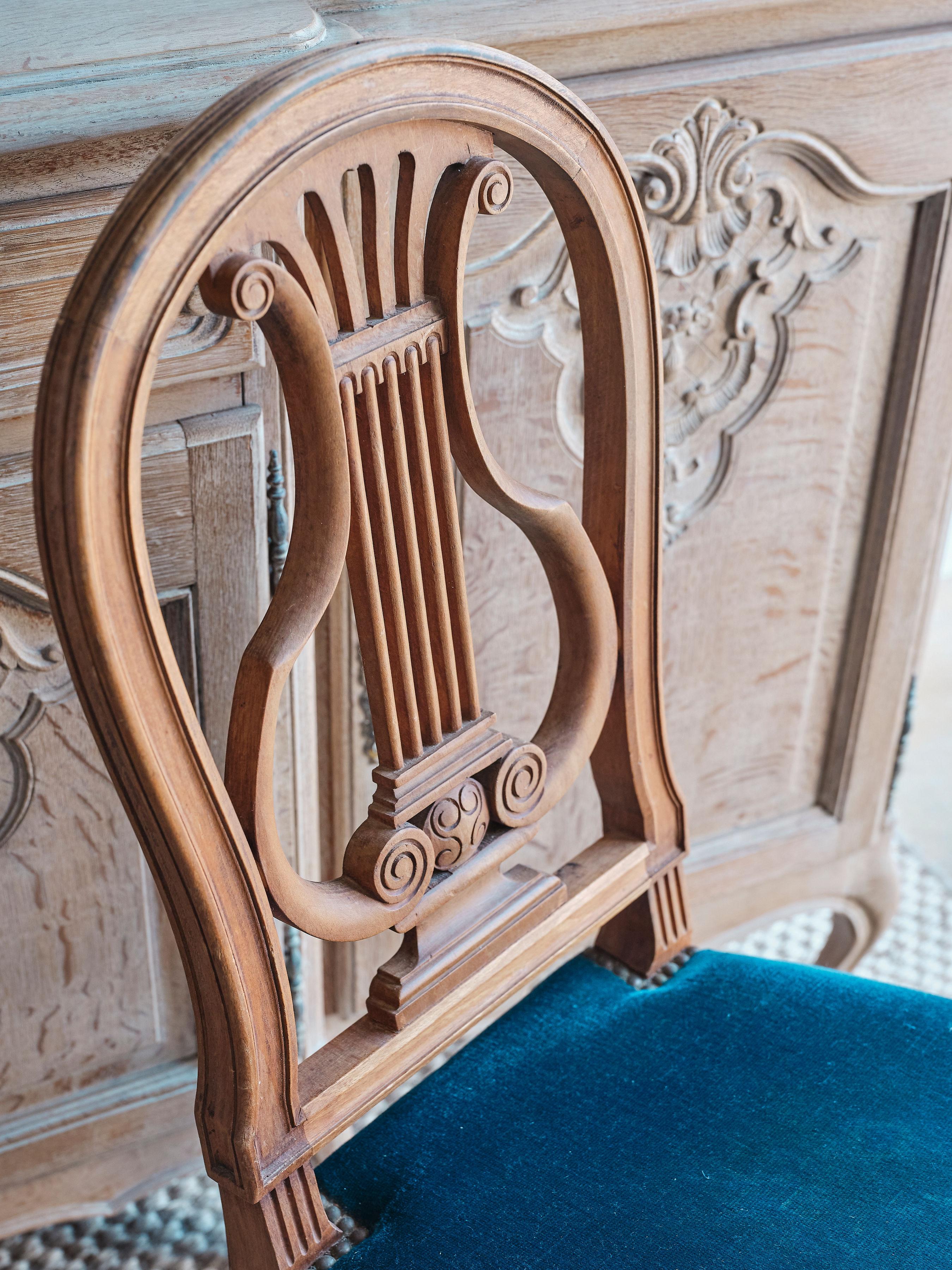 This set of 6 Louis XVI lyra dining chairs features beautiful deep blue velvet seat bottoms with exquisite hand carved wooden seat backs. There is a lovely bronze colored beading around the seat. The legs of the chairs have beautiful hand carved