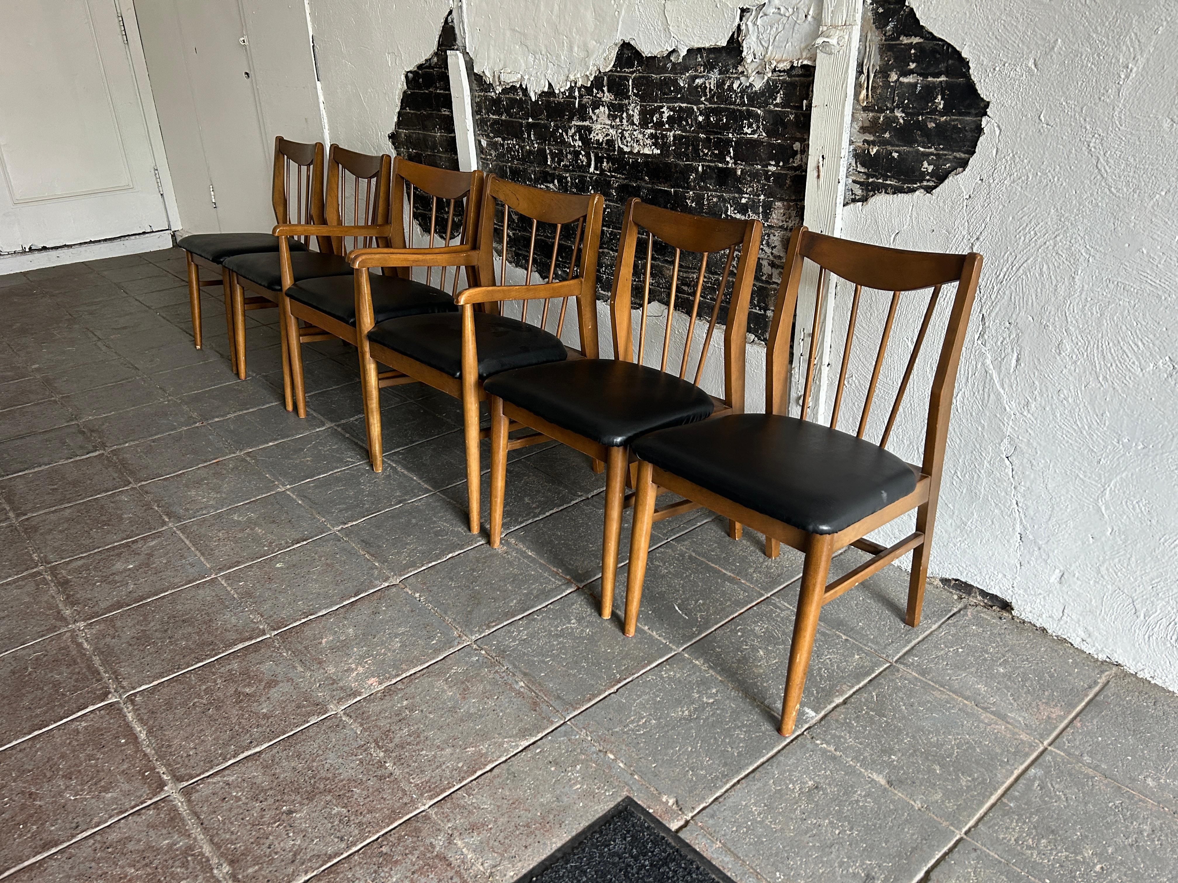 Set of 6 mid century spindle back American modern walnut dining chairs black vinyl Upholstery seat cushions. Great set of dining chairs ready for use or very easy to have reupholstered. Solid wood construction with walnut finish. (2) arm chairs and