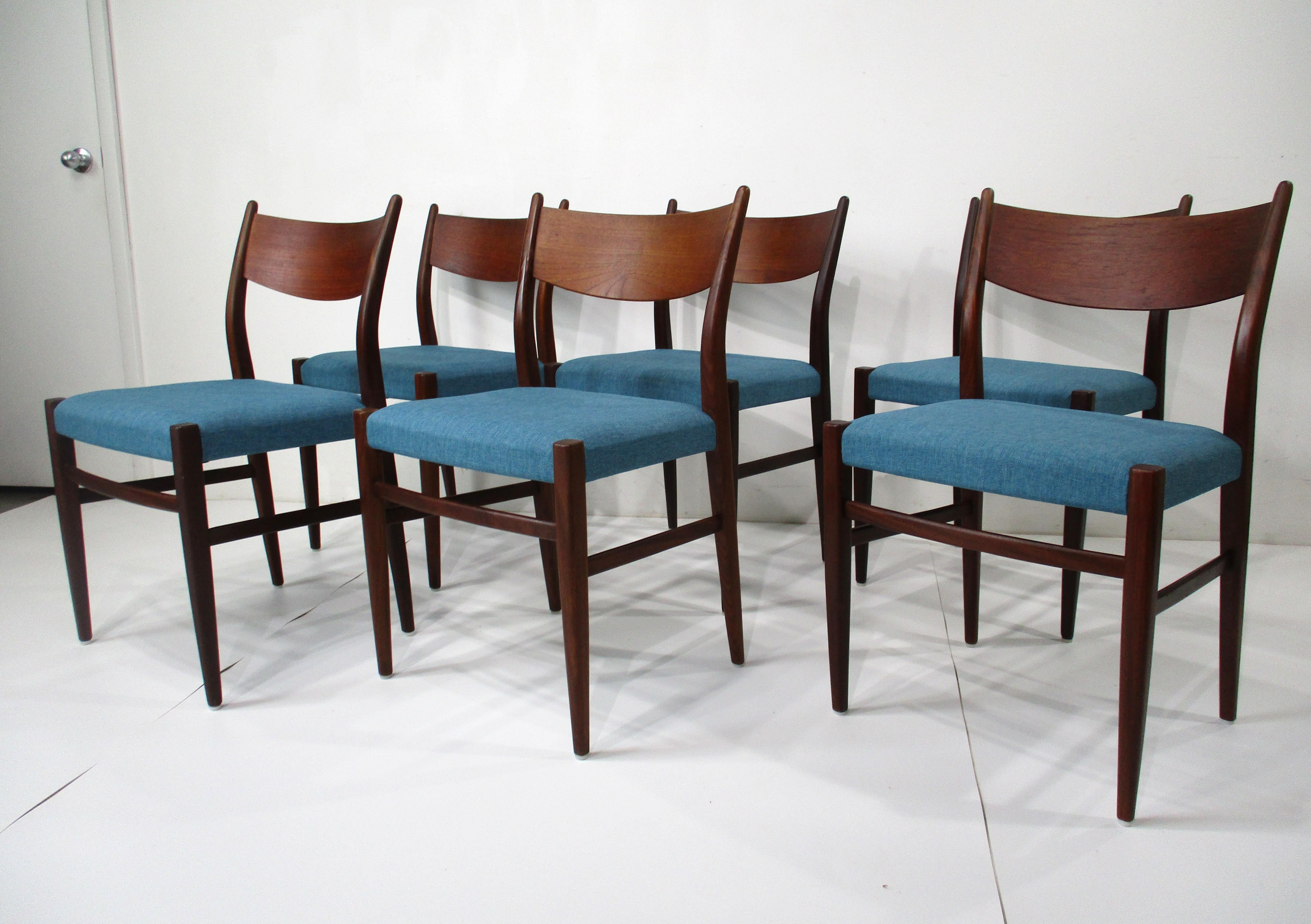 Un set di sei sedie da pranzo con struttura in legno di teak, con schienali curvi per il massimo comfort e sedute rivestite in un tessuto Wood Wood a trama fitta. Queste sedie in stile Minett sono un esempio di qualità superba dei primi design e