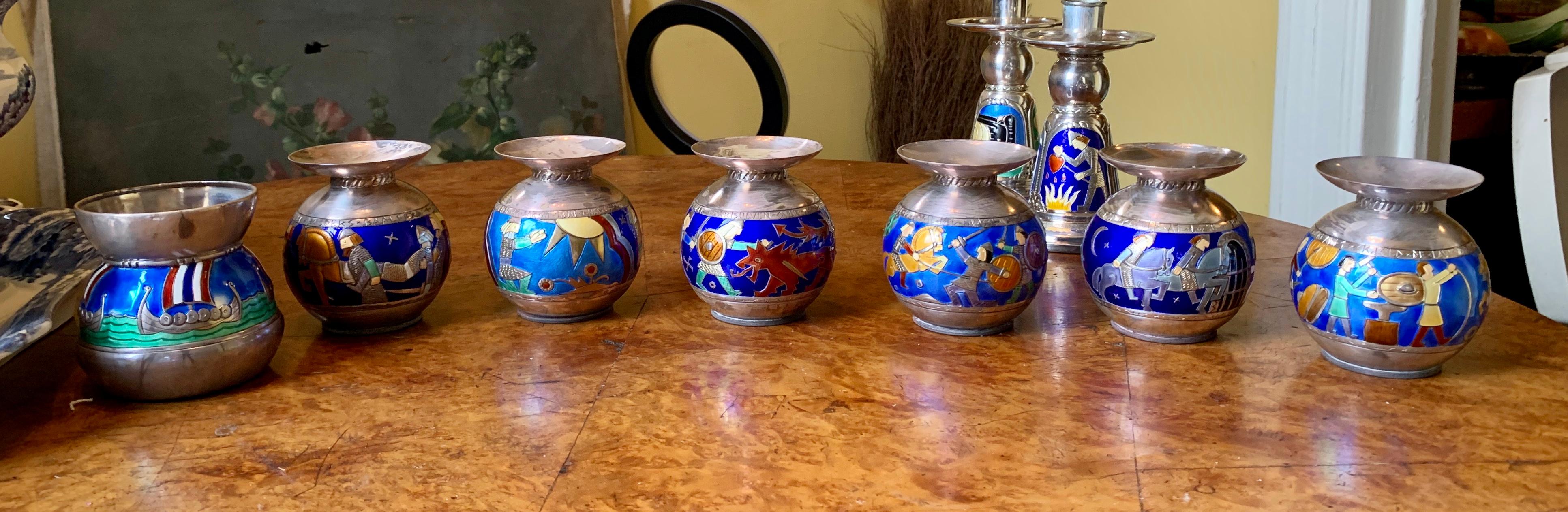 This is an extraordinary rare museum quality set of six Mid-Century Modern Enamel Candlesticks made by the Norwegian maker N.M. Thune of Norway.   Along with the six candlesticks is a matching vase.  Each is adorned with magnificent enamel images