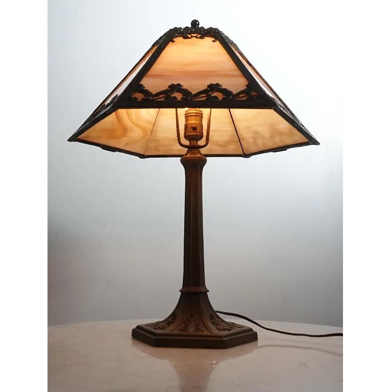 Il s'agit d'une lampe de table Arts and Crafts joliment conçue. Il est simple et épuré avec une forme de tente et 6 panneaux floraux filigranés. Chaque panneau présente une couleur crème -  verre ambré panaché et est éclairé par une seule ampoule E26