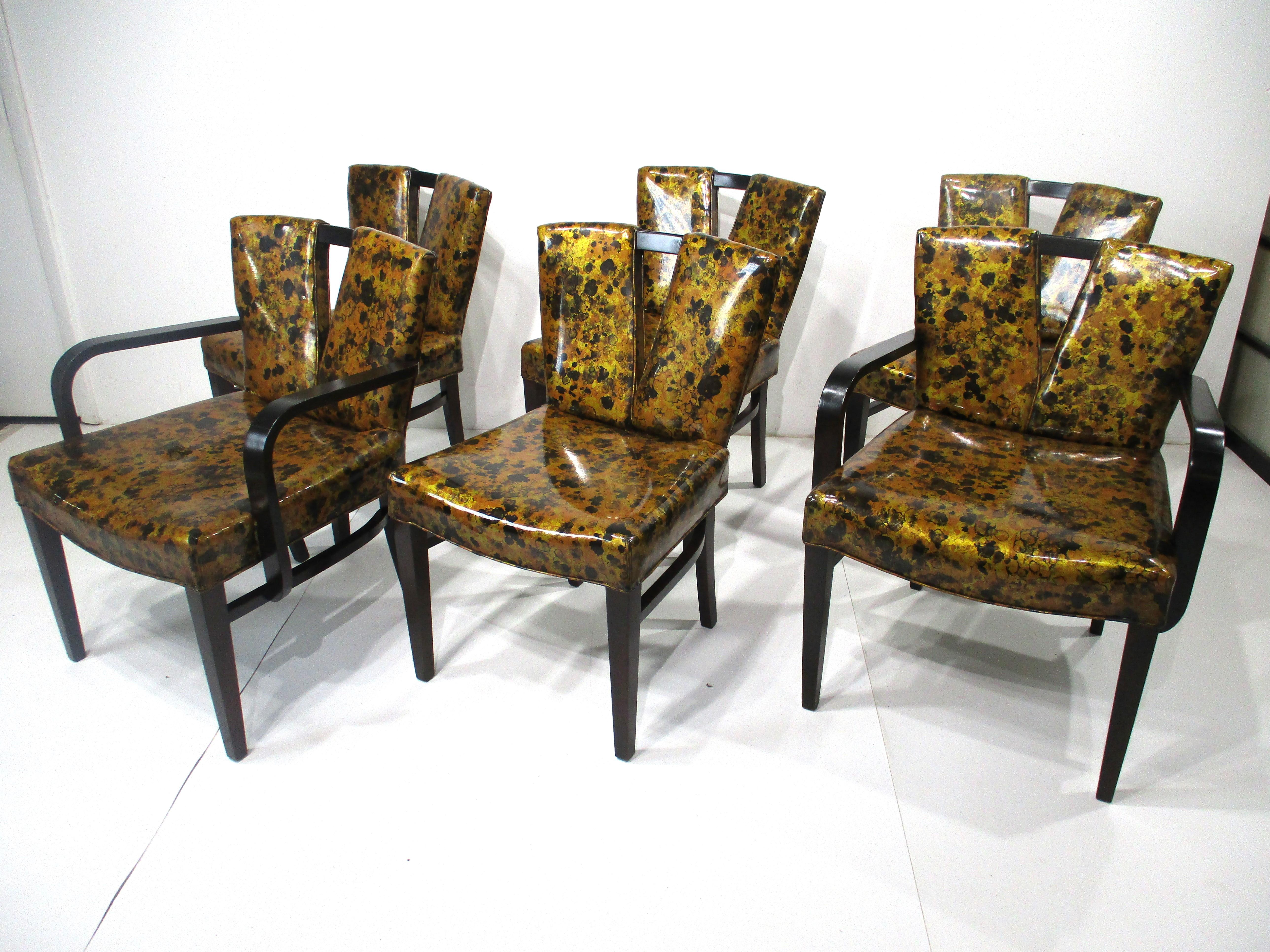 A set of six Corset or V Back dining chairs including two head arm chairs and six side chairs . These very well crafted chairs are upholstered in the original tortoise shell styled leatherette with dark mahogany frames . Designed by Paul Frankl