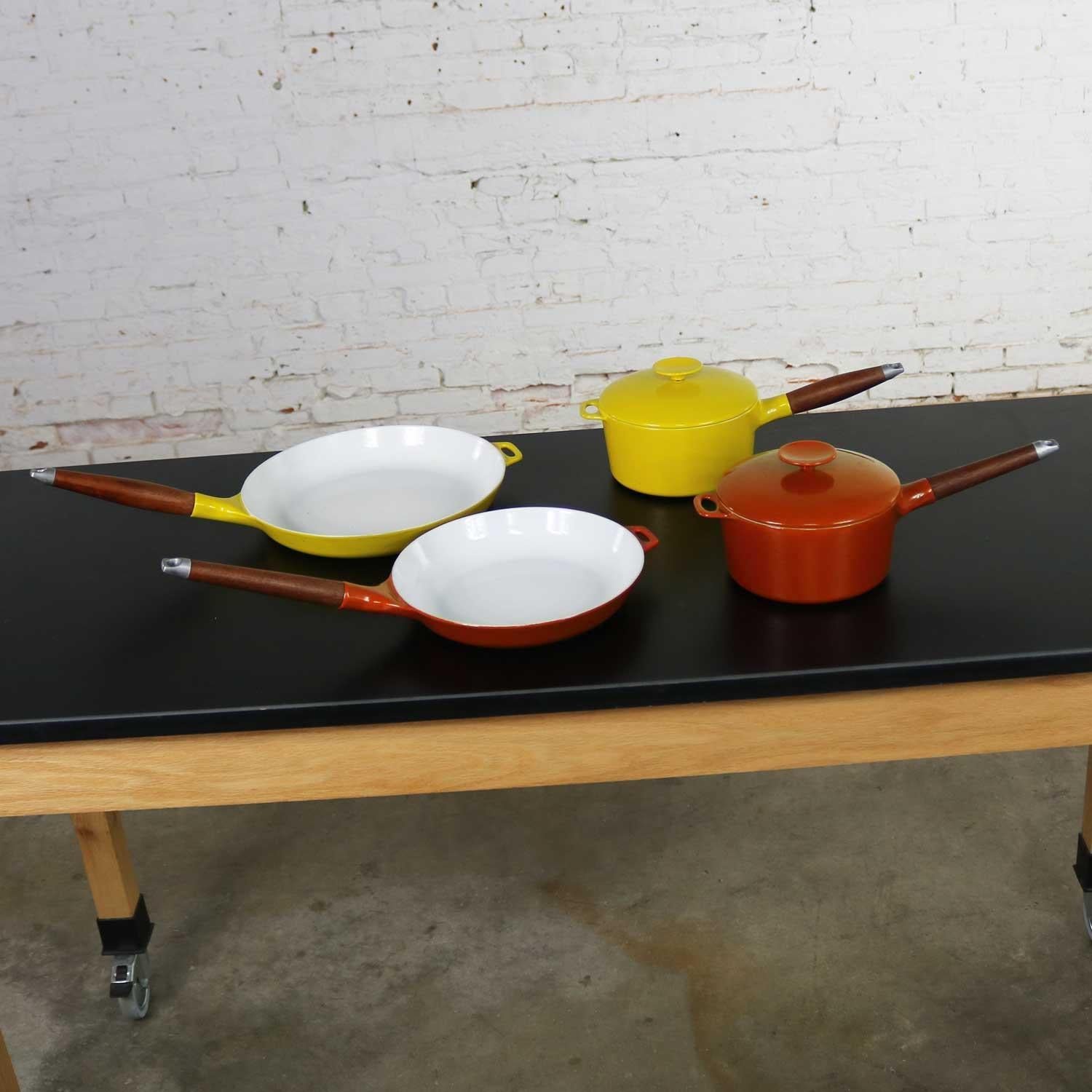 Handsome 6-piece set of midcentury Danish modern enameled cast iron cookware designed by Michael Lax for Copco. Six-piece set includes one seven-inch orange pot and lid, one seven-inch yellow pot and lid, one orange ten-inch skillet, and one yellow