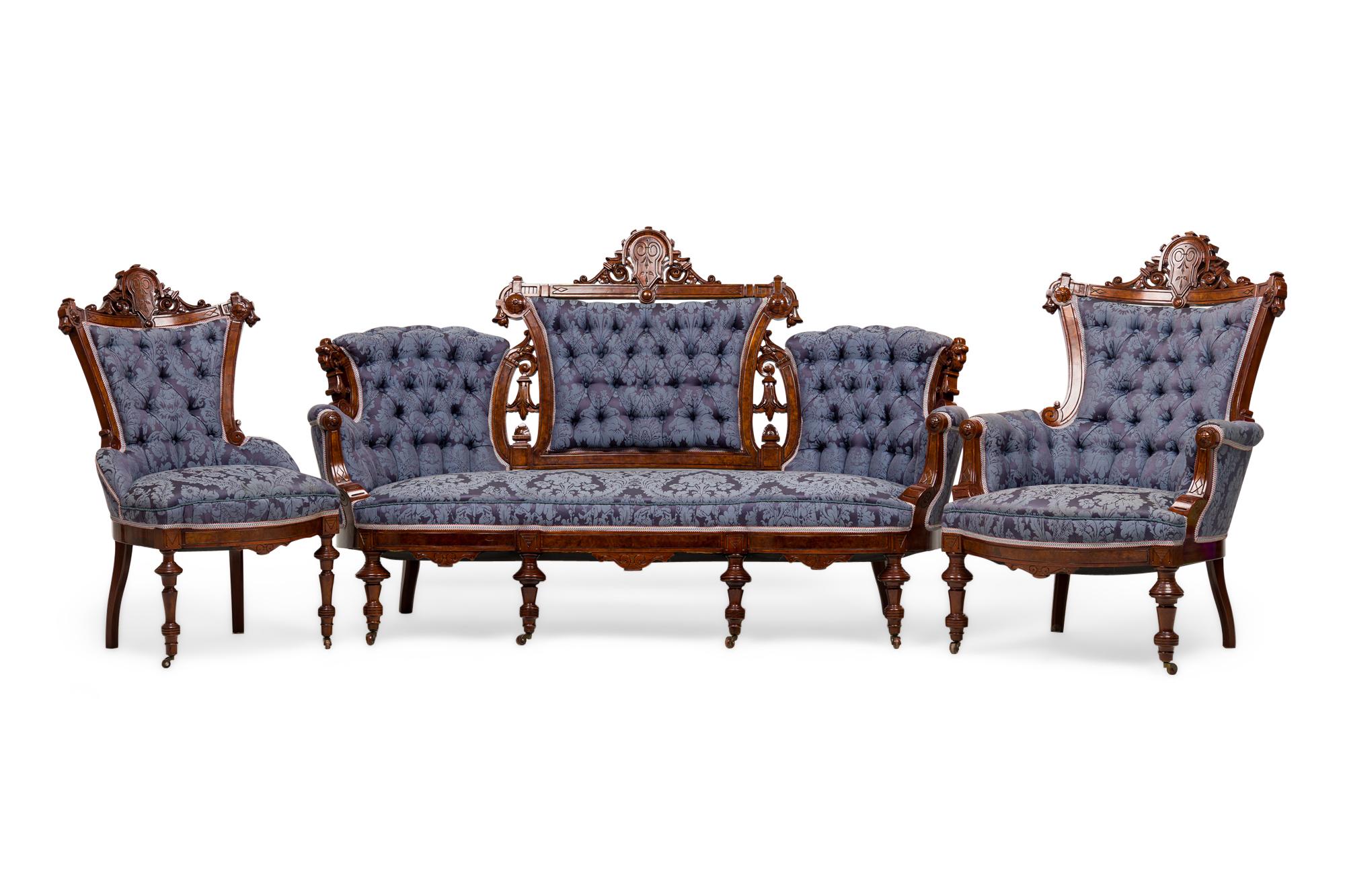 6 Piece American Victorian living room salon set including a settee, an armchair, and 4 side chairs with carved mahogany frames featuring crest pediments and turned legs, upholstered in a two-toned blue damask with a scroll and foliate pattern with
