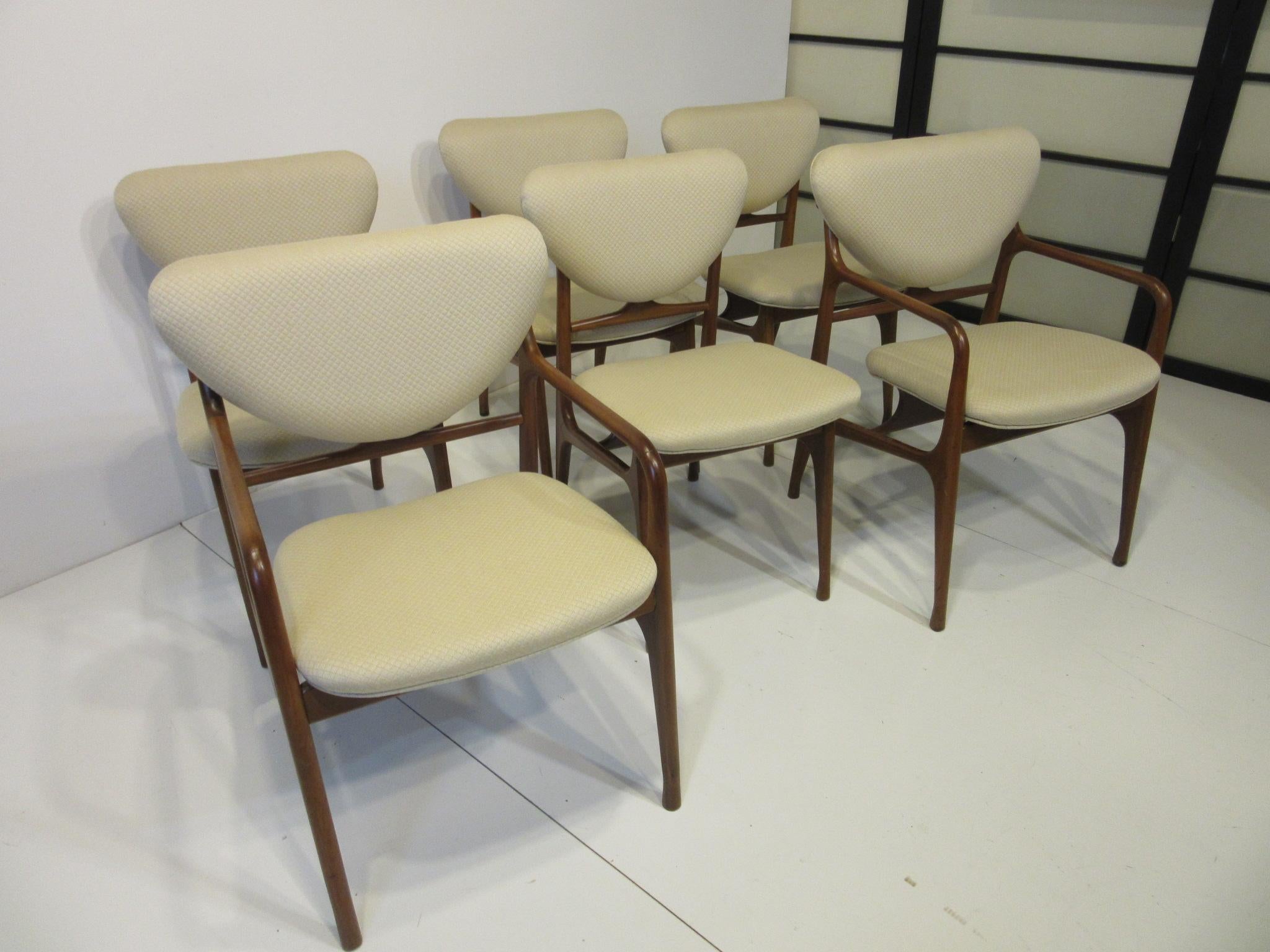 A set of six sculptural mahogany dining chairs with diamond quilted fabric in a creamy tone consisting of two armchairs and four side chairs. The bottom and back cushions have a floating affect making them appear light and airy on the well jointed