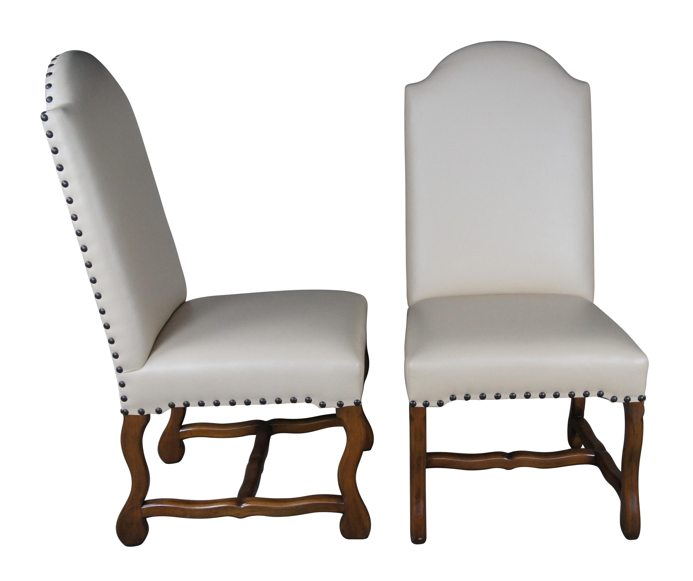 Six Spanish Revival Modern dining chairs featuring domed top with leather seat accented with nailhead trim and linen back, supported by serpentine legs connected by H stretcher.

Dimensions:
22