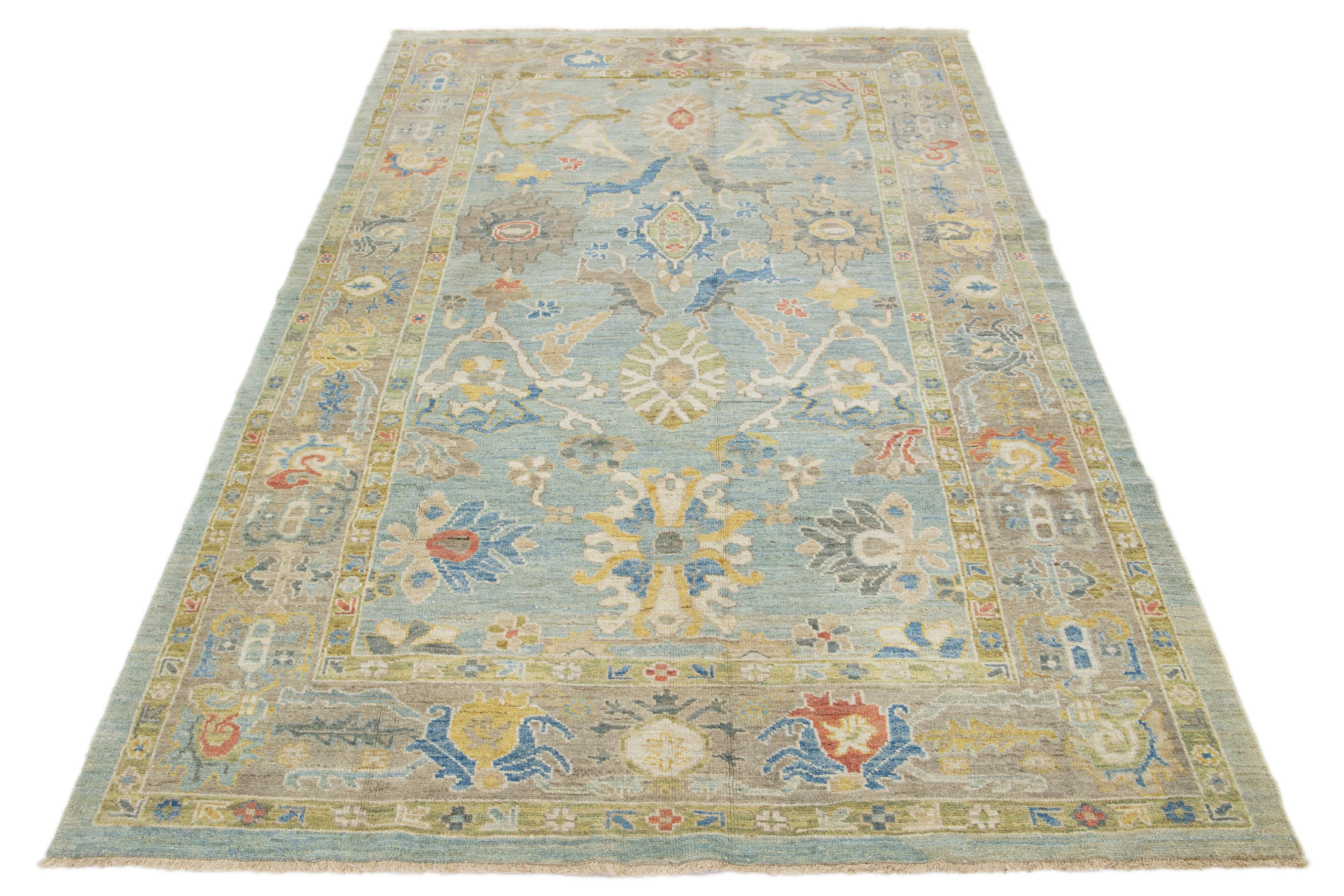 This hand-knotted wool rug features a light blue background with a light brown border and multicolored all-over designs.

This rug measures 6'4'' x 10'10''.