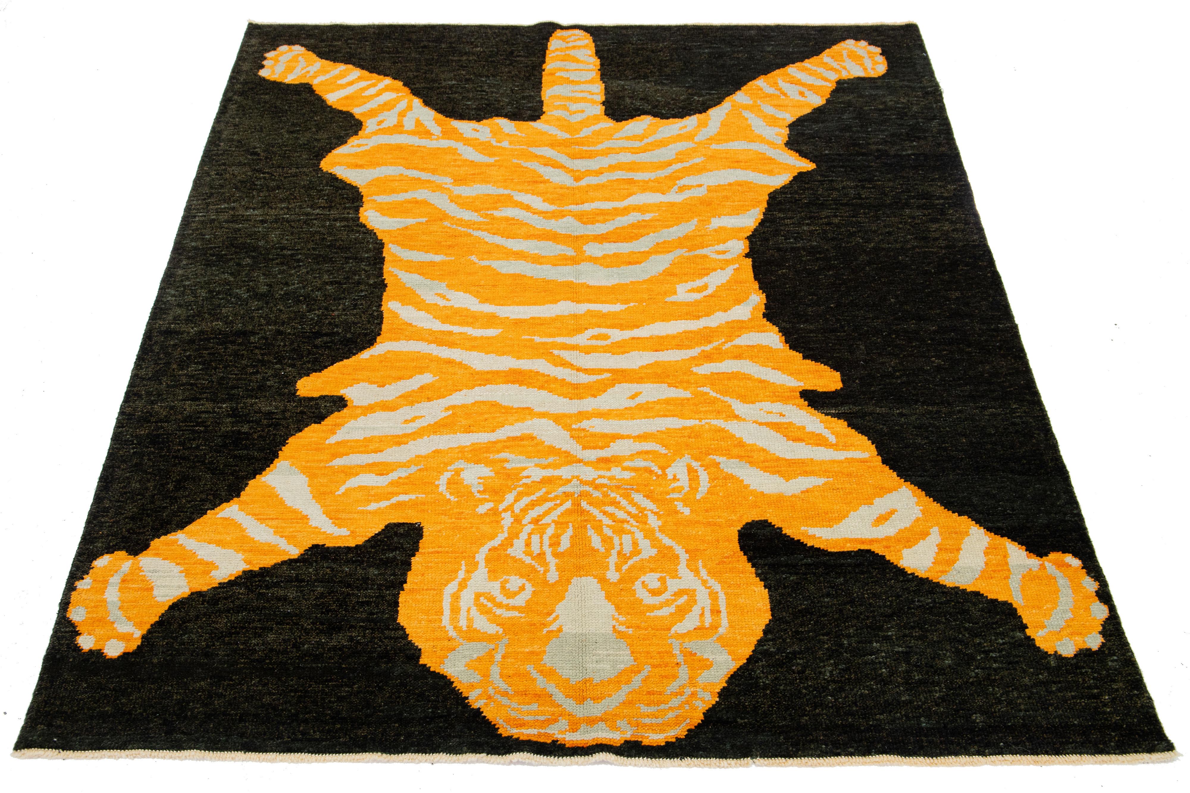 This beautiful Turkish Art Deco wool rug features a black field with orange and beige accents, depicting a stunning tiger pictorial design.

This rug measures 6'1