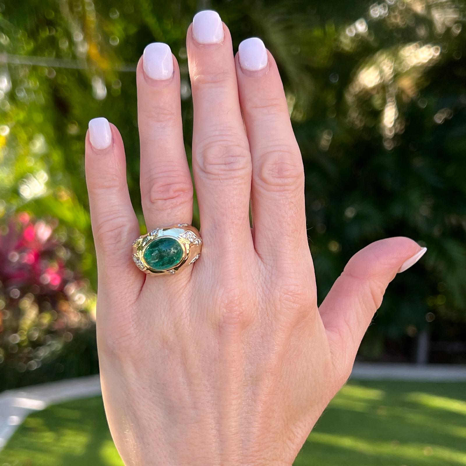 Emerald diamond cocktail ring handcrafted in 18 karat yellow gold. The cabochon oval emerald weighs approximately 6.0 carats and is bezel set with 30 surrounding round brilliant cut diamonds weighing approximately .50 carat total weight. The