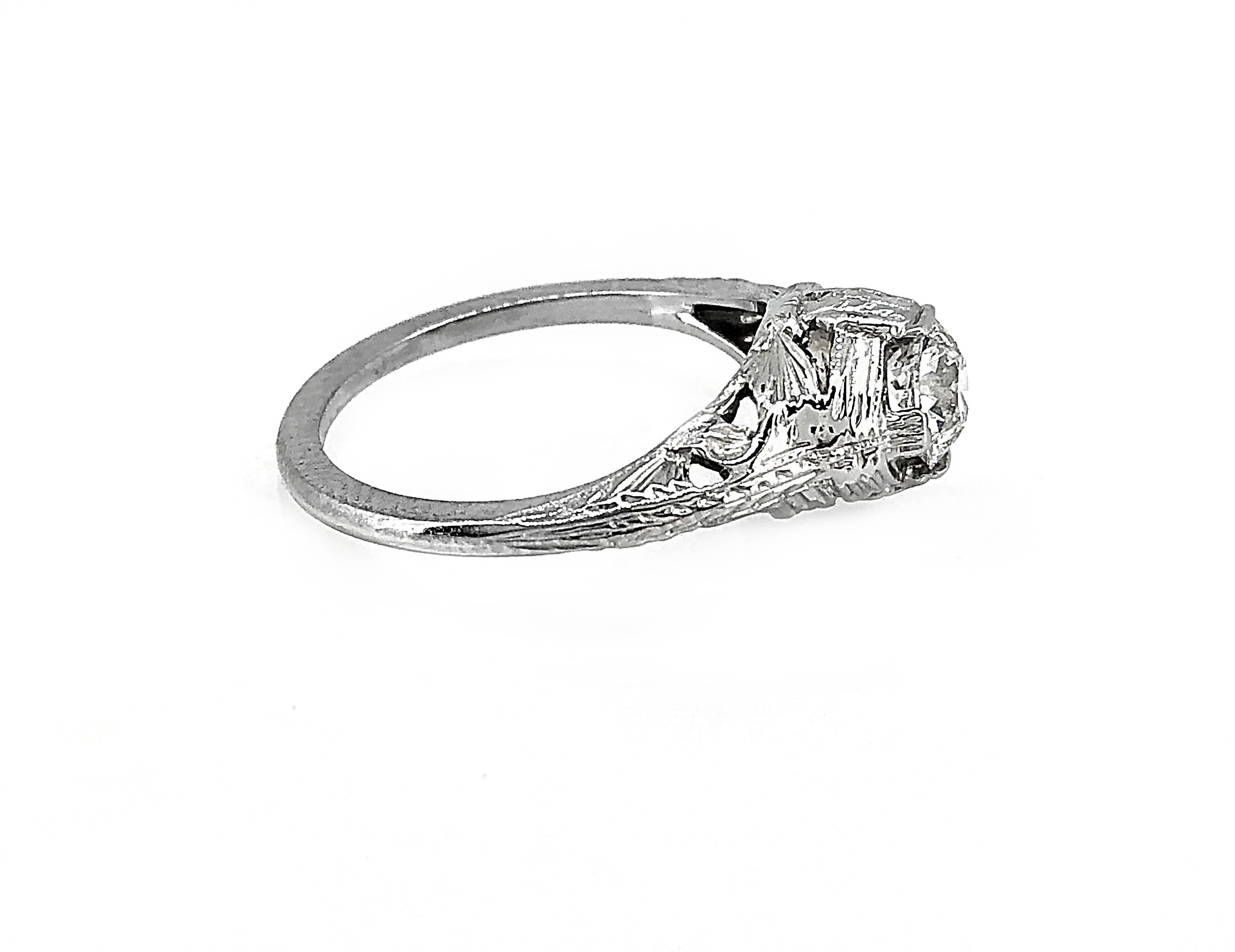 A masterfully filigreed and engraved 18k White Gold Art Deco diamond Antique engagement ring that features a .60ct. apx. European cut diamond with SI1 clarity and G color. This beautifully constructed ring is artfully designed and is sure to be a