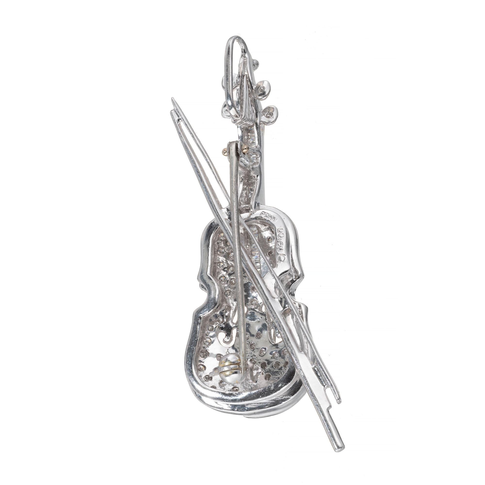 Three-dimensional violin brooch pendant in solid platinum with pave and channel set diamonds.

24 straight baguette diamonds H-I SI, approx. .30ct
64 round diamonds H-I SI, approx. .30cts 
Platinum 
Stamped: PT950
Hallmark: D 0.60
Top to bottom: