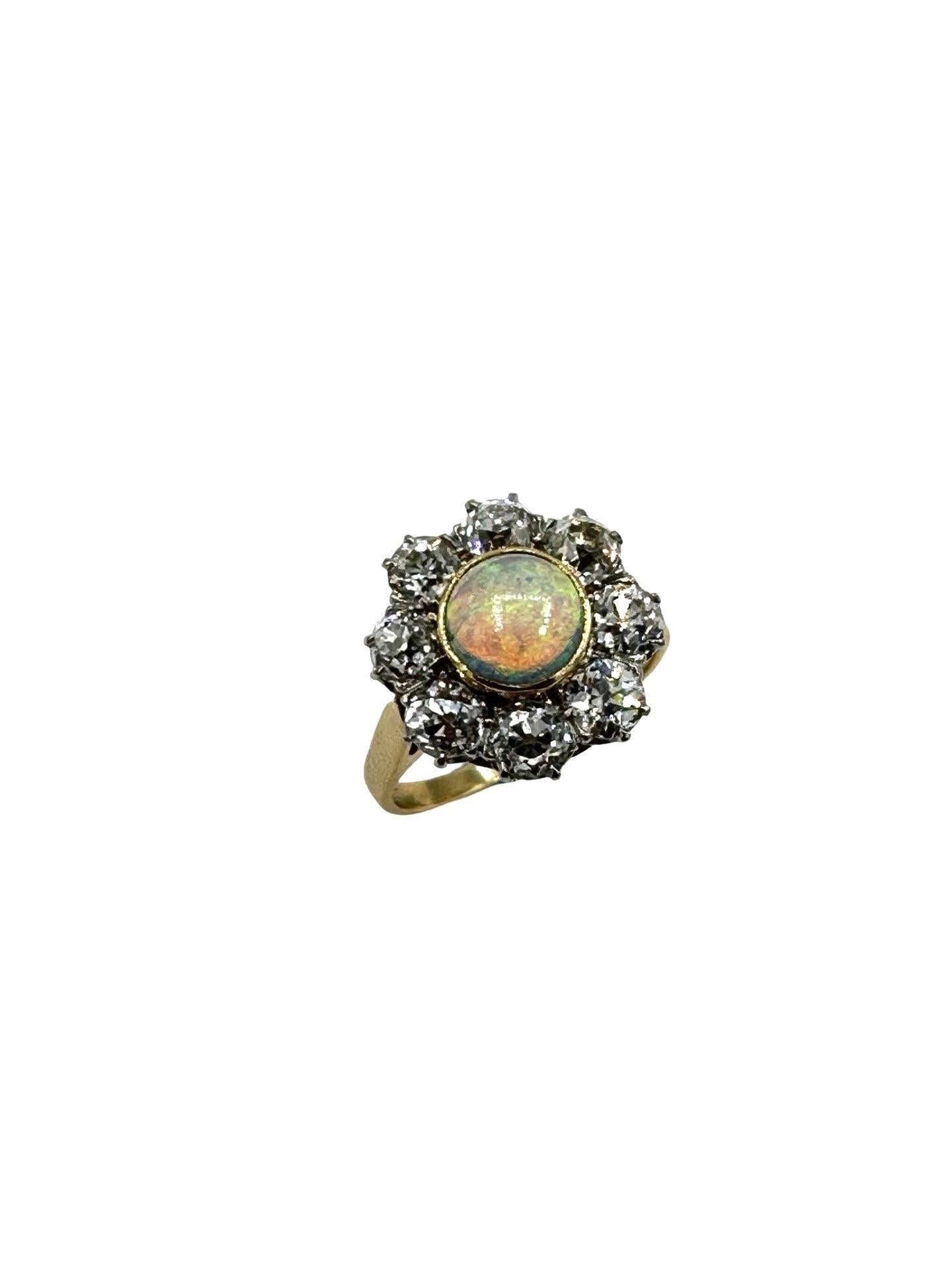 A stunning Opal and Diamond fashion ring!  The cabochon cut Opal displays mainly blues and greens, with flashes of red, surrounded by a single row of old European cut Diamonds, set in platinum.  The Diamonds are graded as H-I color, VS-SI1 clarity,