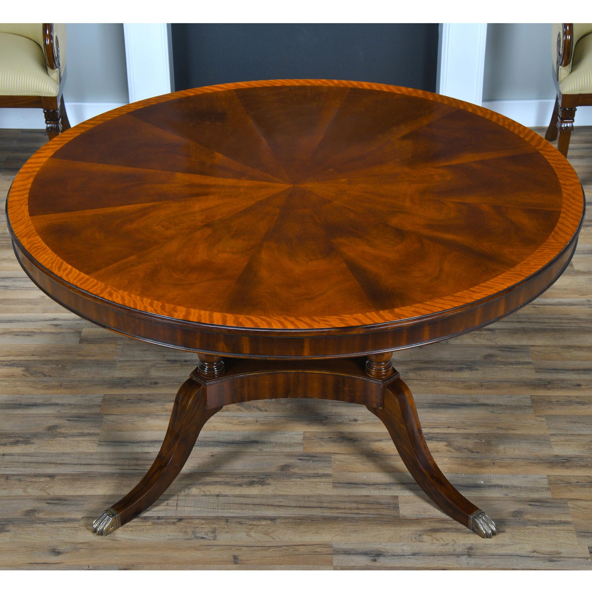 The 60 inch Round Dining Table is produced with a figured mahogany field and satinwood banding on the top which makes for an interesting contrast. The elegant base is pillared over top a central platform resting on shaped and tapered legs capped
