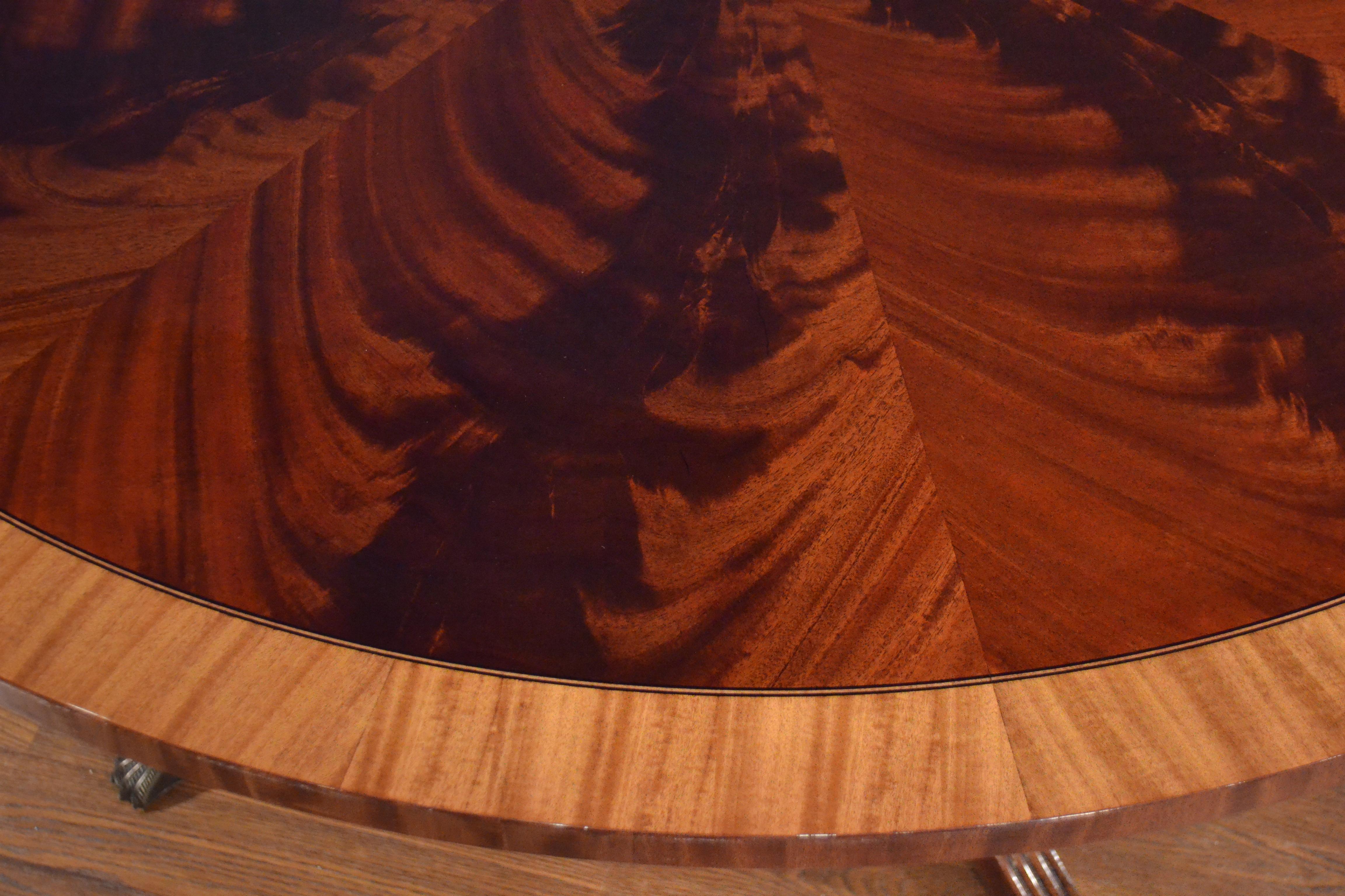 Mesa de comedor redonda tradicional de caoba hecha a medida en la tienda de Leighton Hall. Presenta un campo de caoba crotch swirly de África Occidental de corte radial y un borde de madera de satén. Hay una incrustación de ébano y arce blanco que