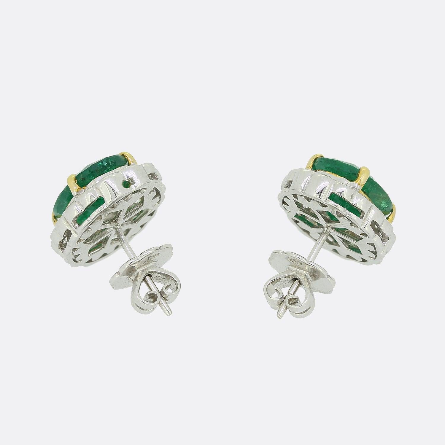 Dies ist ein Paar Ohrstecker aus 18 Karat Weißgold mit Diamanten und Smaragden. Jeder Ohrring beherbergt einen oval geschliffenen Smaragd, der von einem Halo aus sechzehn runden Diamanten im Brillantschliff in einer Clusterformation umgeben ist. Die